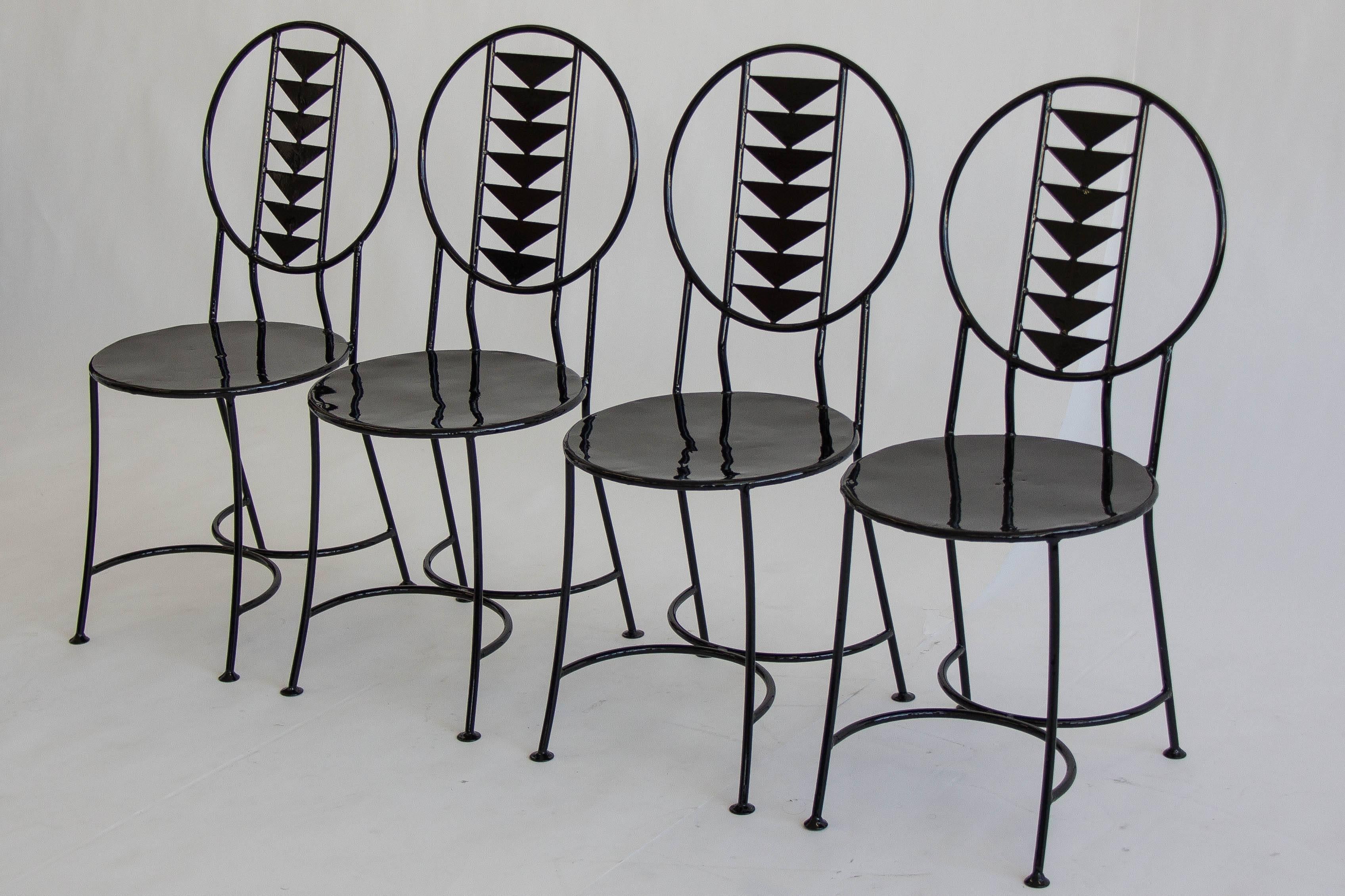 Set of four unique wrought iron chairs in the style of Frank Lloyd Wright's Midway Chair, designed in 1914. These solid chairs feature a circular seat and Prairie style triangular pattern on the back. Chairs have been powder coated with a glossy