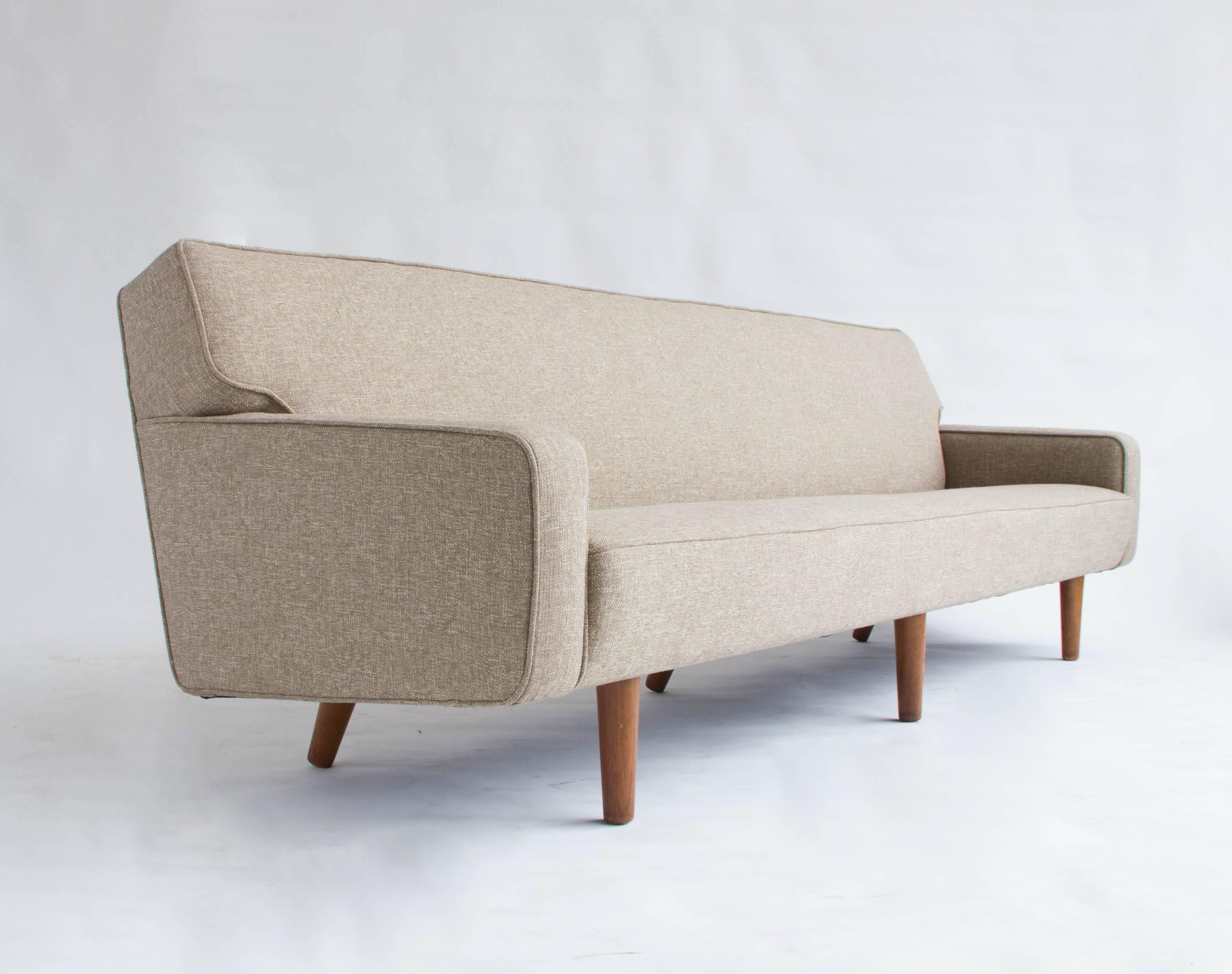Perfectly restored AP33 model sofa, designed by Hans Wegner for AP Stolen in the 1950s. The integrated seat and backrest lend a streamlined effect and the piece is fully finished on the back to allow free-standing installation if desired. Piece has