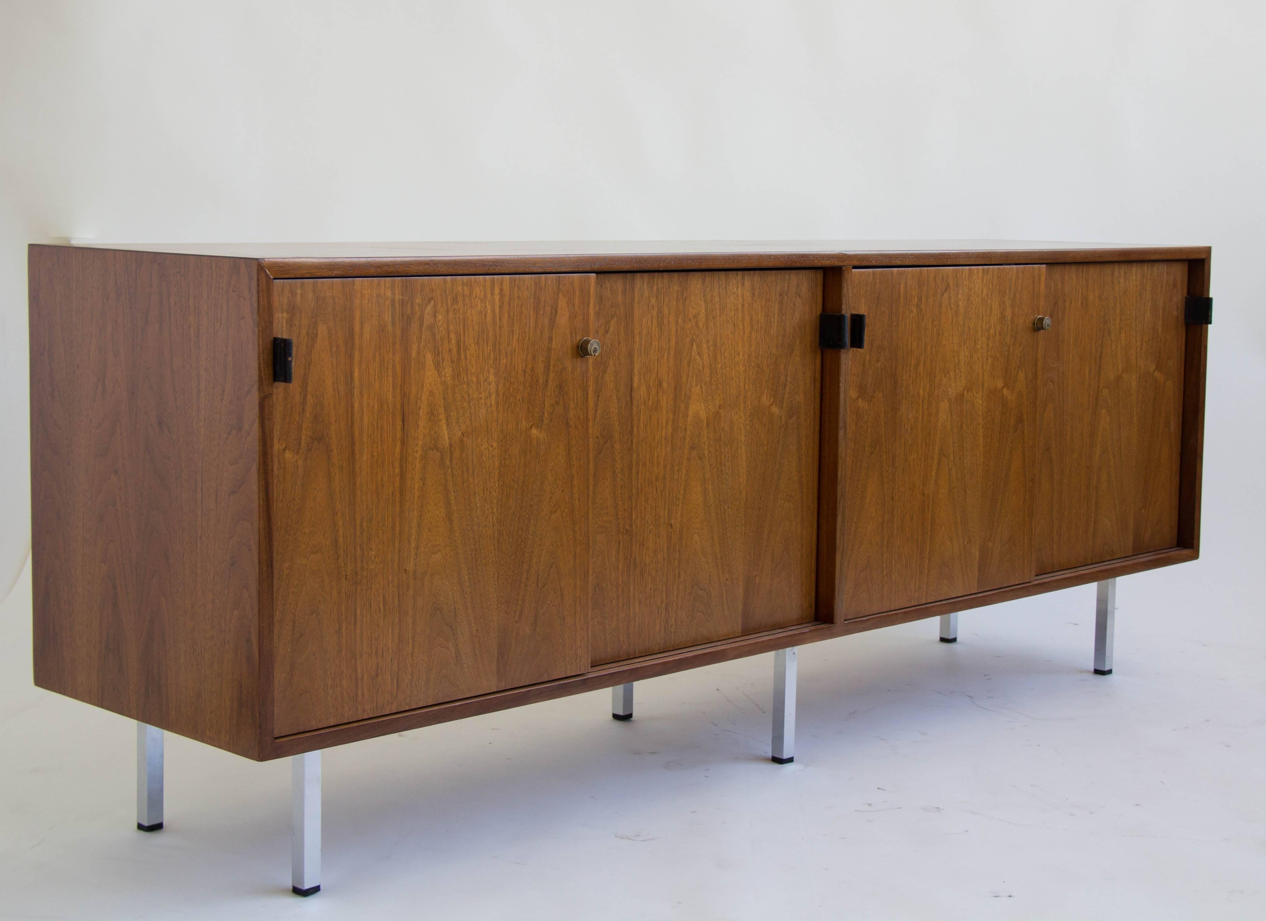 Four-compartment credenza by Florence Knoll. Each compartment has an adjustable shelf and closes with sliding doors. Two locks secure the compartments if necessary. The flat drawer pulls are made of top-stitched black leather. The credenza is