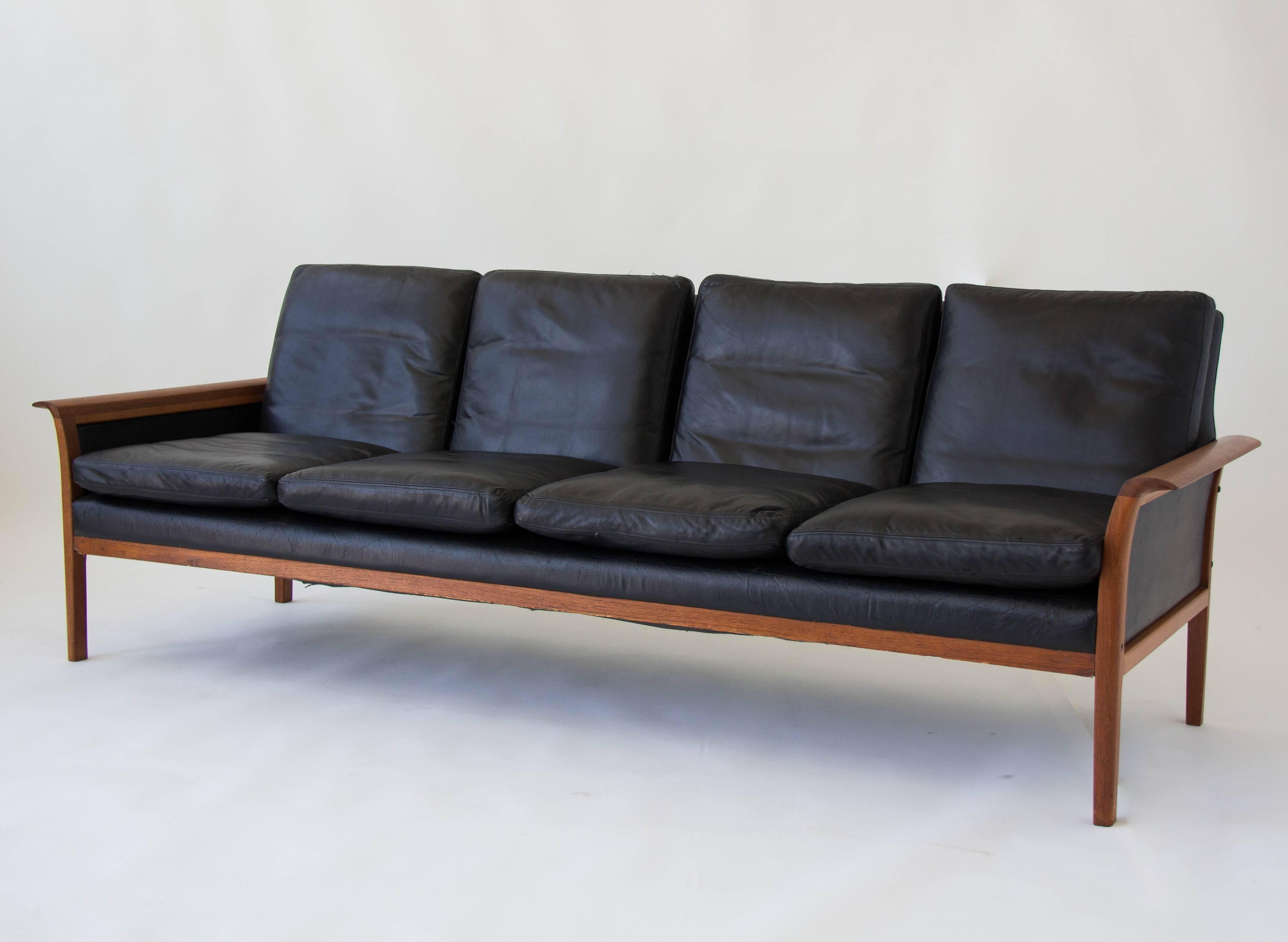 Norwegian four-seat sofa with teak frame, upholstered in original black leather, designed by Knut Sæter and manufactured by his own company, Vatne Lenestolfabrikk. The teak frame has curved armrests and back and side panels are also covered in black