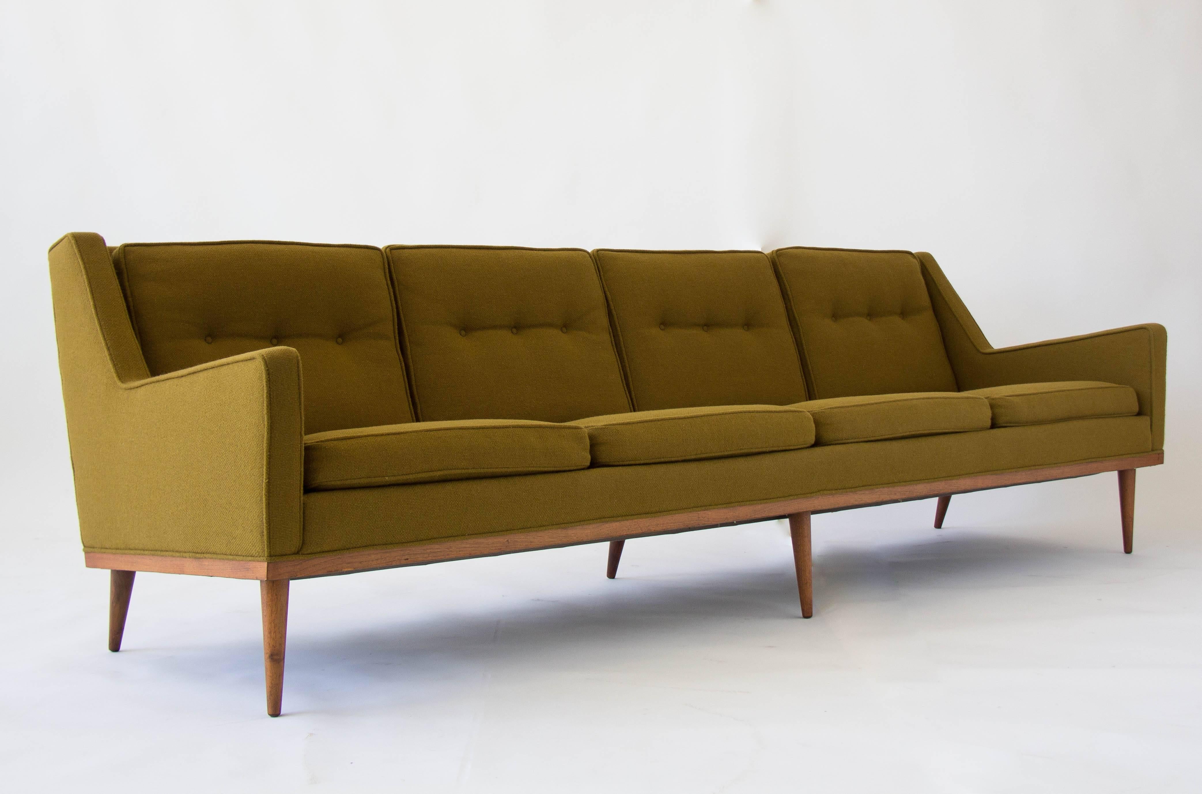 Milo Baughman designed the Articulate collection including this sofa for James, Inc. of North Carolina, Thayer Coggin's first manufacturing venture. It features an upholstered case with angled armrests atop a teak platform. The rear legs are kicked