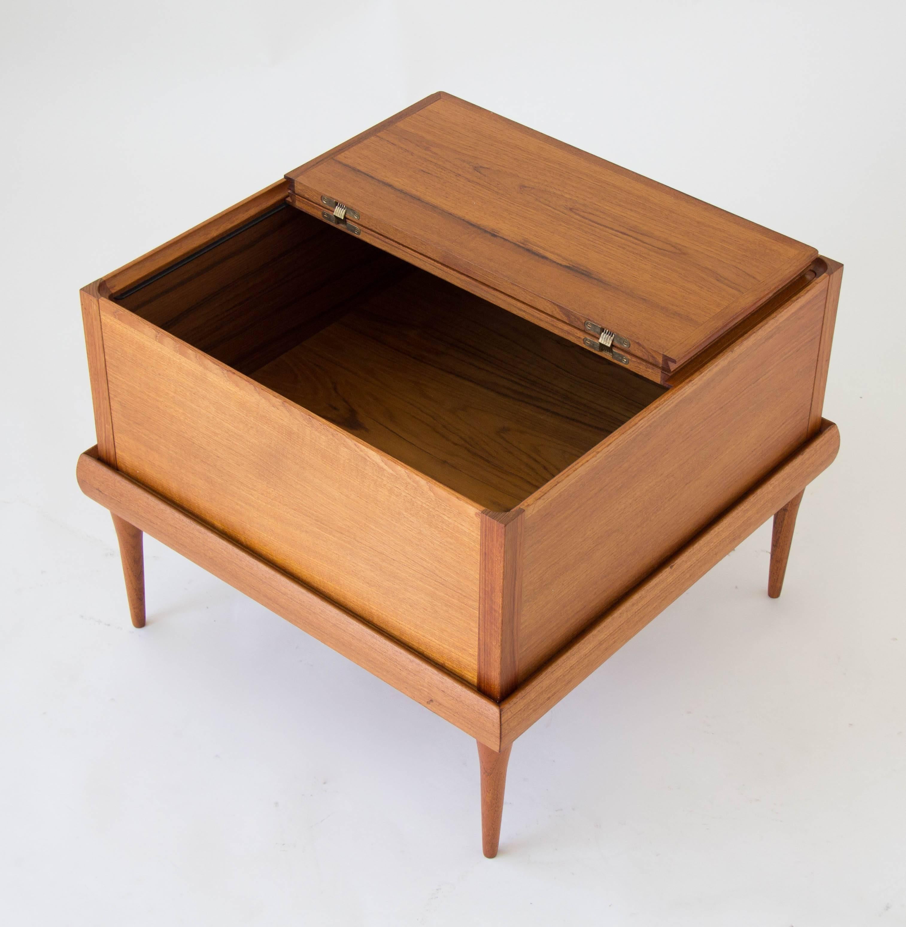 Teak storage cube from H. W. Klein’s modular seating group for Bramin Møbler of Denmark. The free-floating box sits in a matching teak square table with tapered legs. The lid has a center hinge, opening on both sides to facilitate access to the