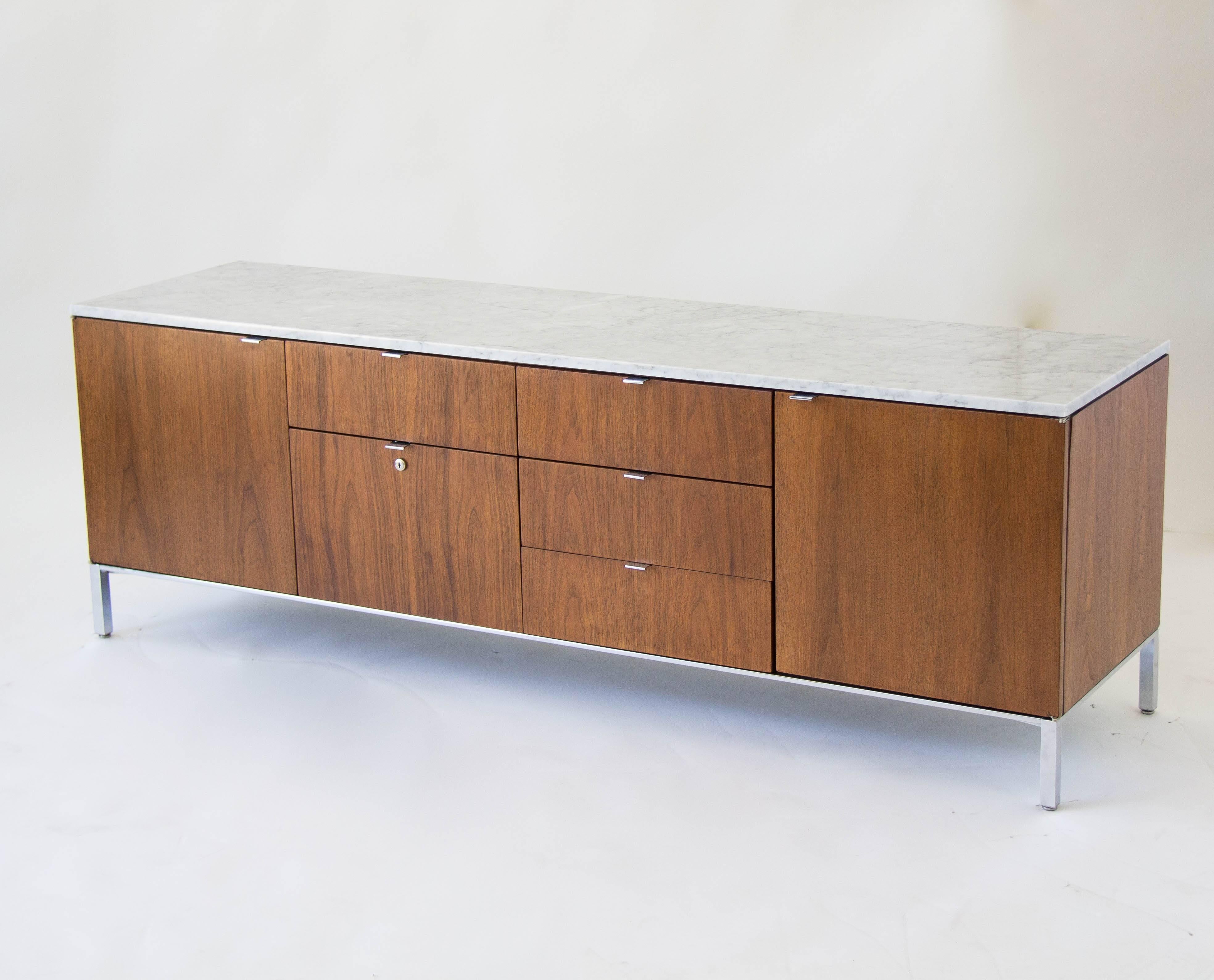 A four-position walnut credenza framed in with chrome legs and a marble top, by American manufacturer Stow Davis, of Grand Rapids. The outermost compartments each have a sliding walnut shelf, while the inner right has three evenly-spaced drawers and