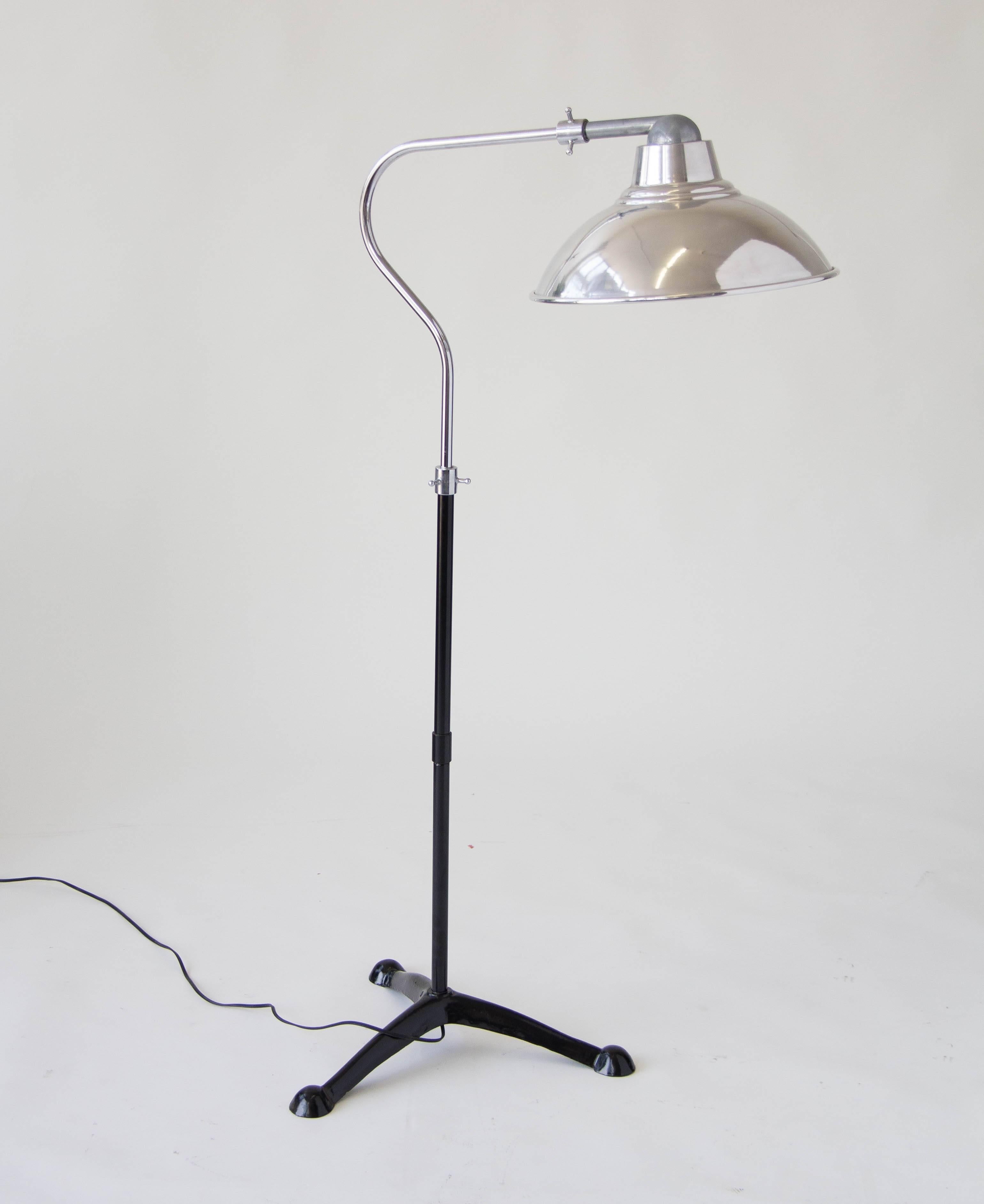 A vintage floor lamp with aluminum shade and an exaggerated gooseneck, on a black enameled metal base with three legs. Lamp shade rotates 360º and the column height is adjustable. 

Condition: Excellent vintage condition; aluminum parts have