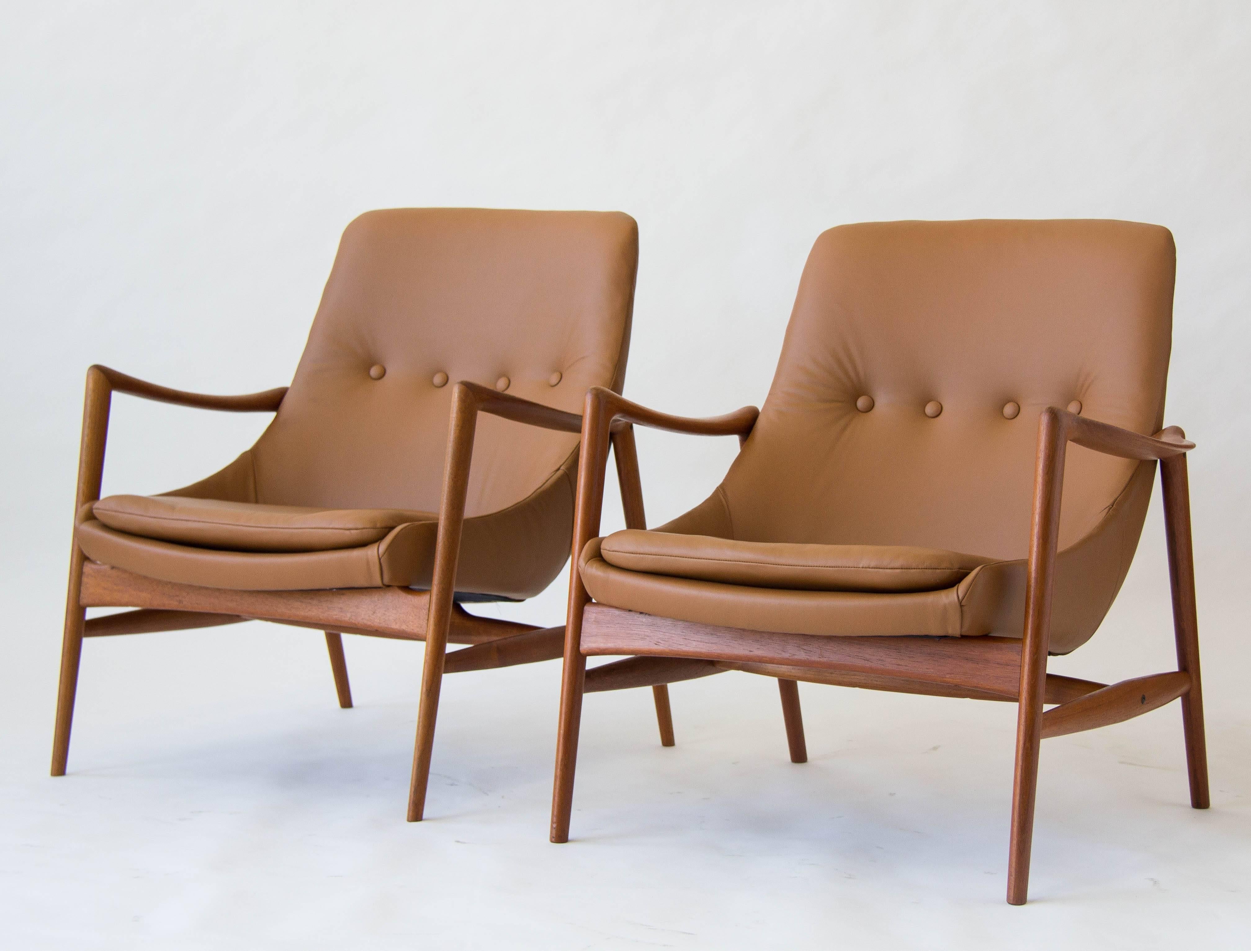 Imported by Peter Wessel beginning in 1962, these Norwegian-designed lounge chairs by Rolf Rastad and Adolf Relling have sculpted teak frames with curved armrests. Each chair has an unattached seat cushion and a tufted backrest and is upholstered in