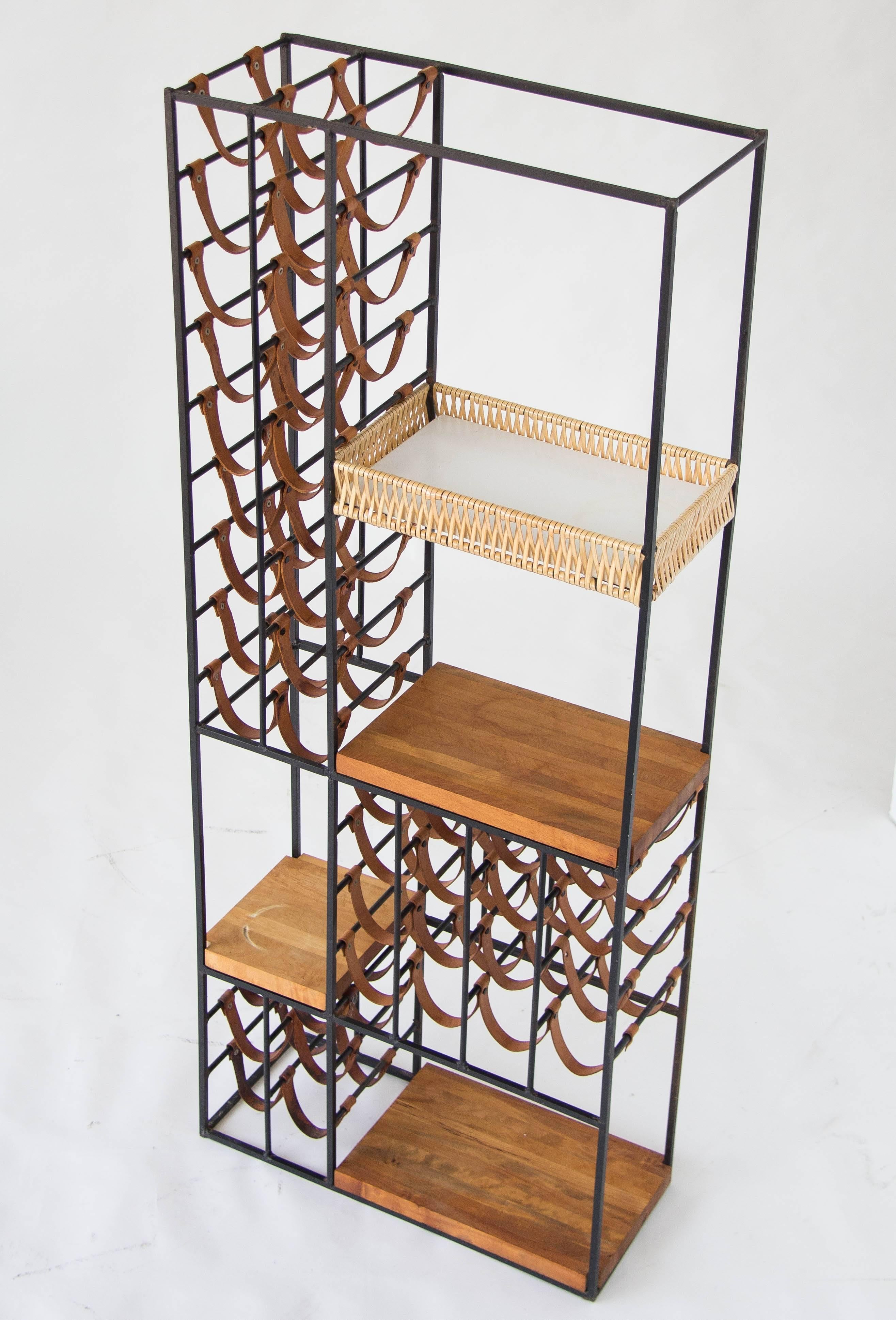 A 40-bottle wine rack designed by Arthur Umanoff and produced by Shaver Howard. The unique design has an iron frame with rows of leather slings for holding wine bottles, interspersed with three butcher-block shelves of solid wood, and one wicker