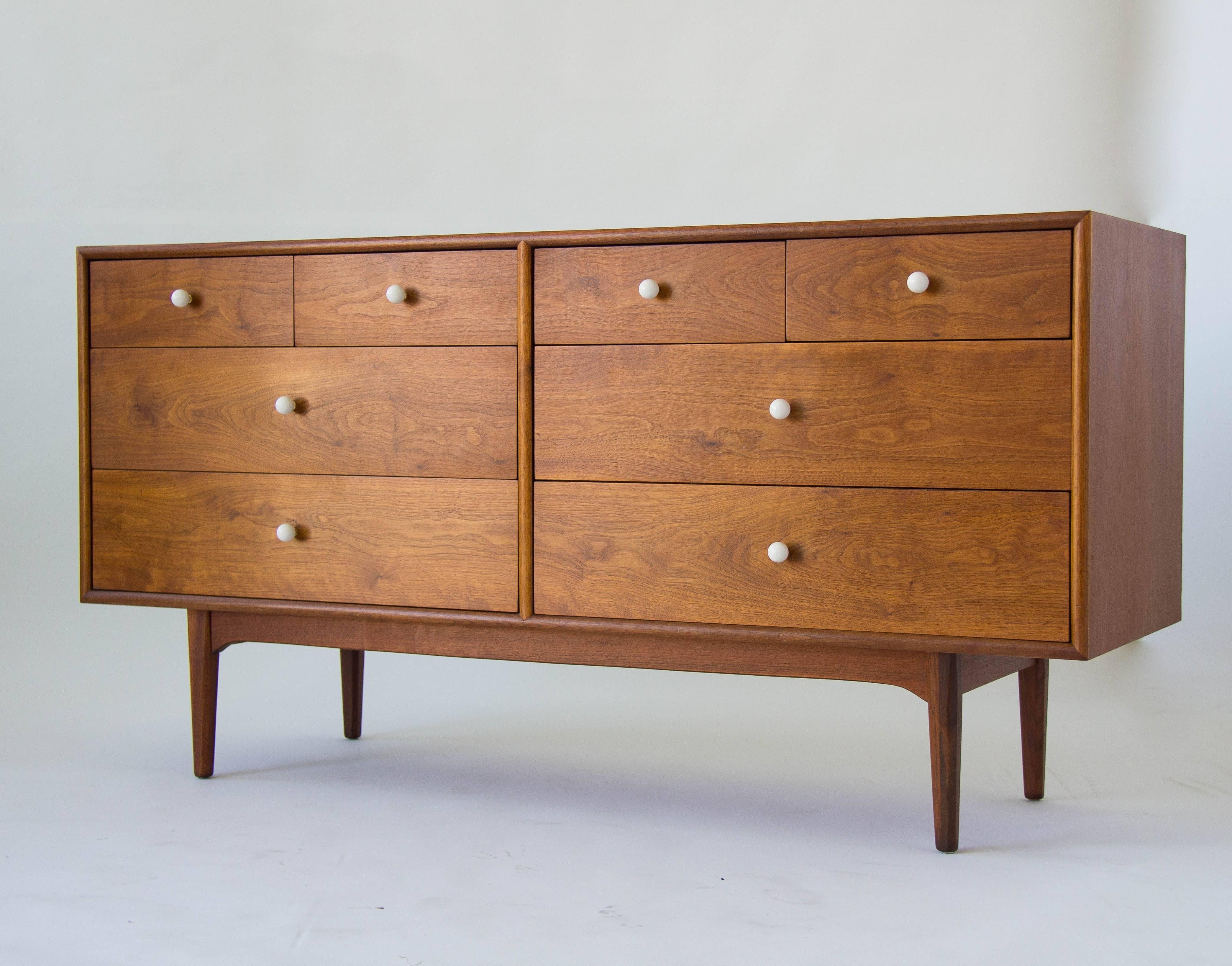 Walnut dresser from Drexel’s popular Declaration collection by Kipp Stewart and Stewart MacDougall. This example has a walnut case holding eight-drawers with original white ceramic knobs on brass spacers. Each of the two-drawer stacks has two large