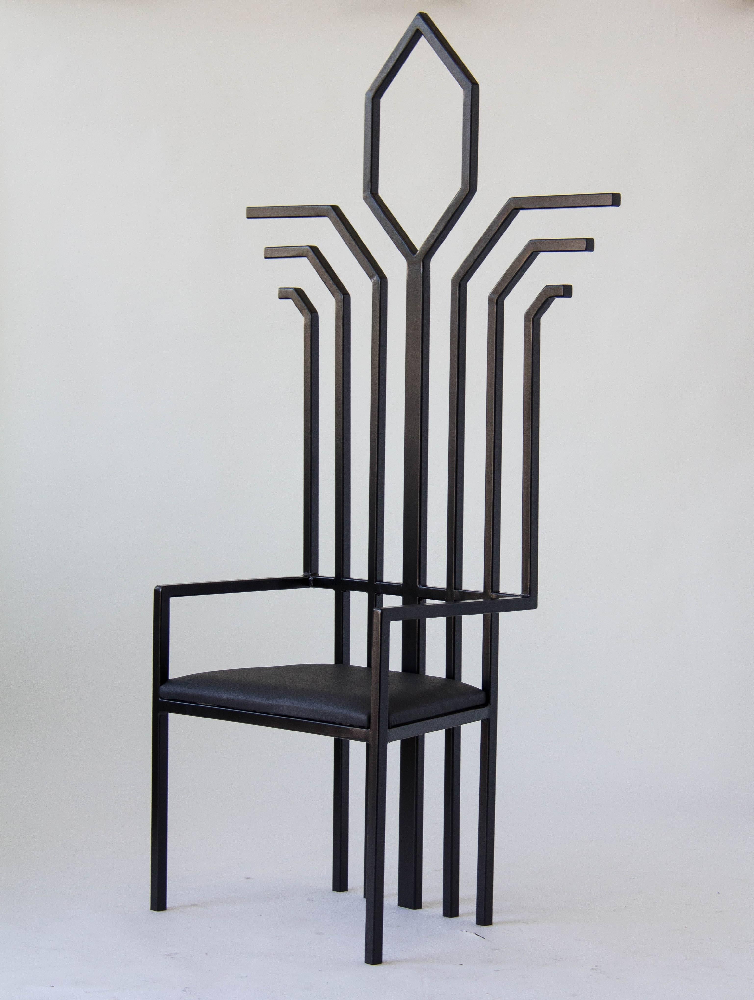 Unsigned entryway chair with a slatted back of squared steel tubing, powder coated black. The focal point of the chair is a large keyhole detail at the peak of its high back. The seat is upholstered in black leather. 

Condition: Excellent