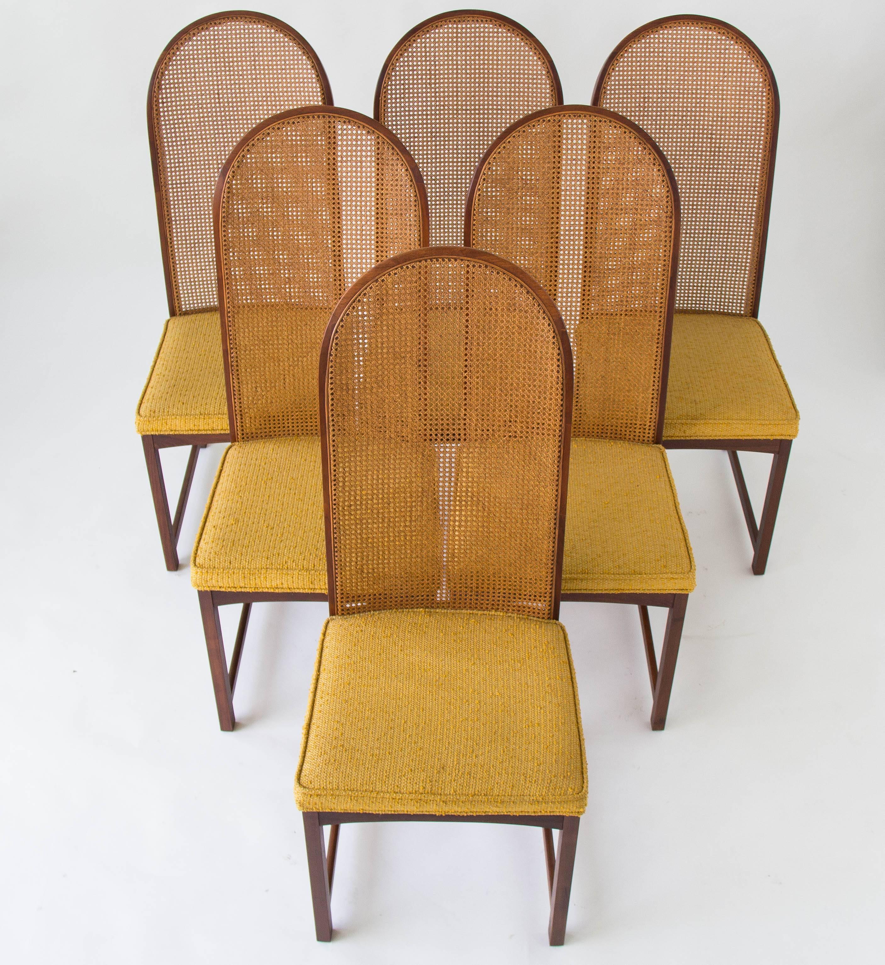 Designed by Milo Baughman for Directional, these high-backed dining side chairs were produced by a Directional contractor, Johnson Furniture Co. from 1963-1968. Each chair has an arched backrest of woven cane, and an upholstered seat in the original