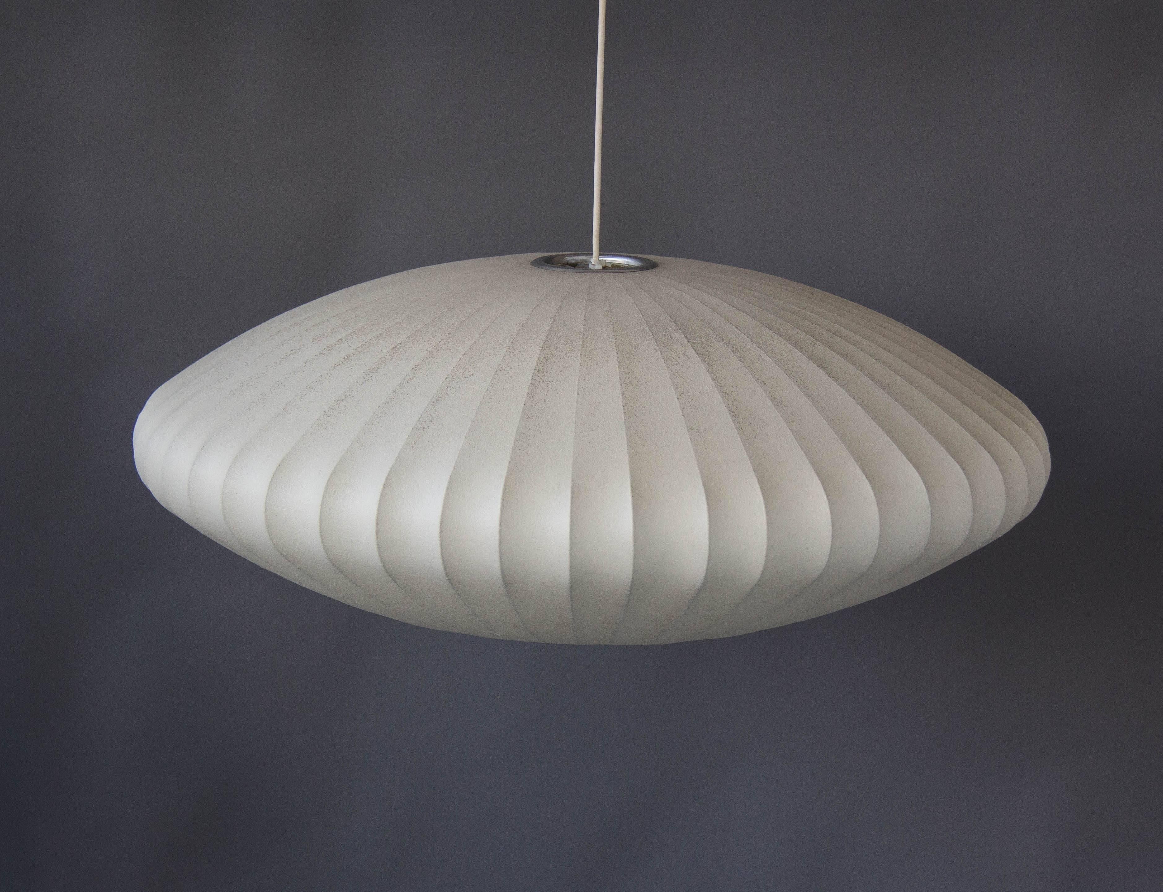 An original H-727 bubble lamp (now referred to as “Saucer Lamp” variant) designed by George Nelson for Howard Miller in 1947. The lightweight steel frame is covered in the original plastic webbing. There is a ball chain with a small wooden pull to
