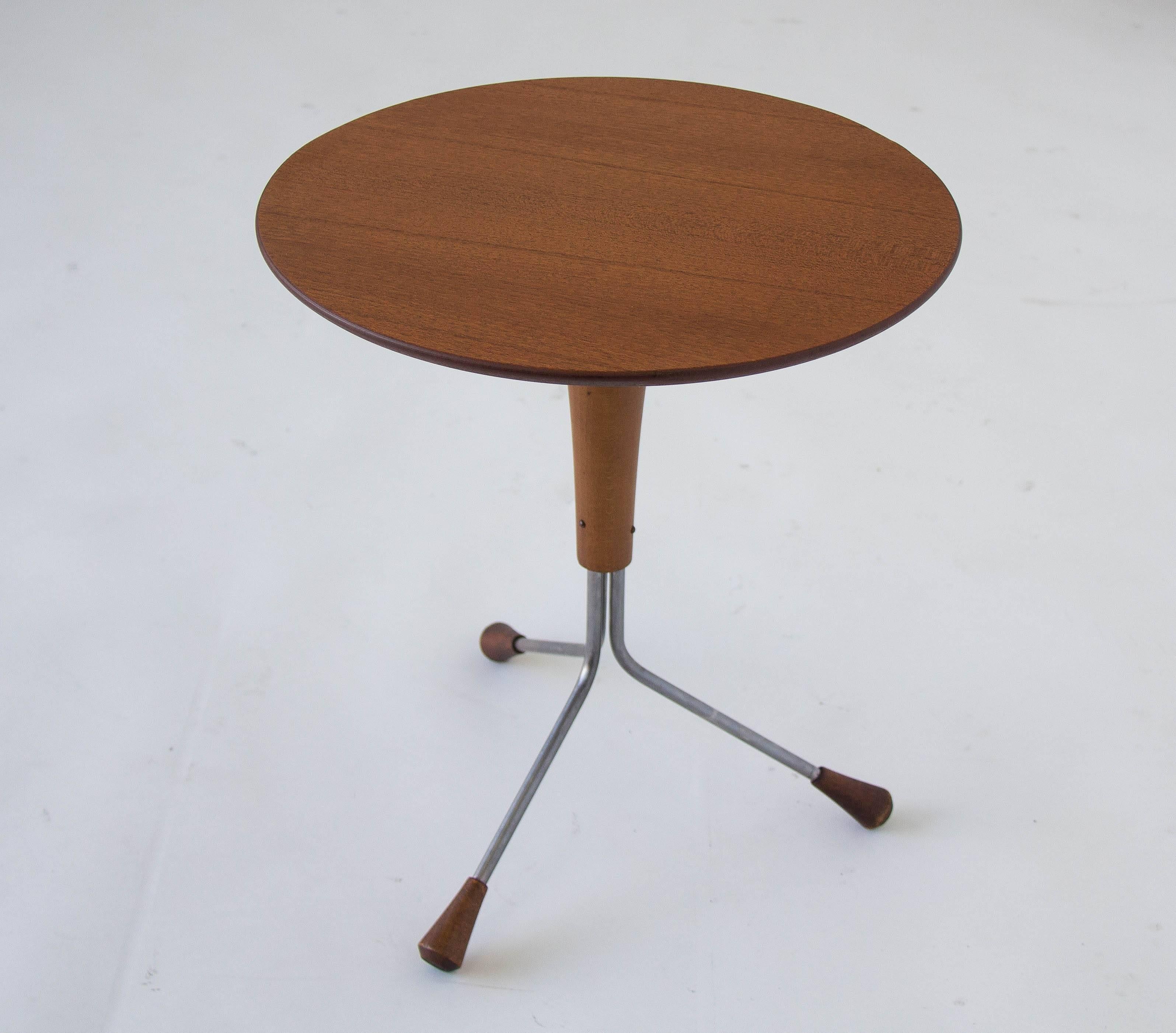 A small round teak side table, designed by Albert Larsson for his company Alberts Tibro of Sweden. The table has a tripod base of polished steel legs with teak feet. Label on underside of tabletop identifies the model as the “013 Snack Table” and