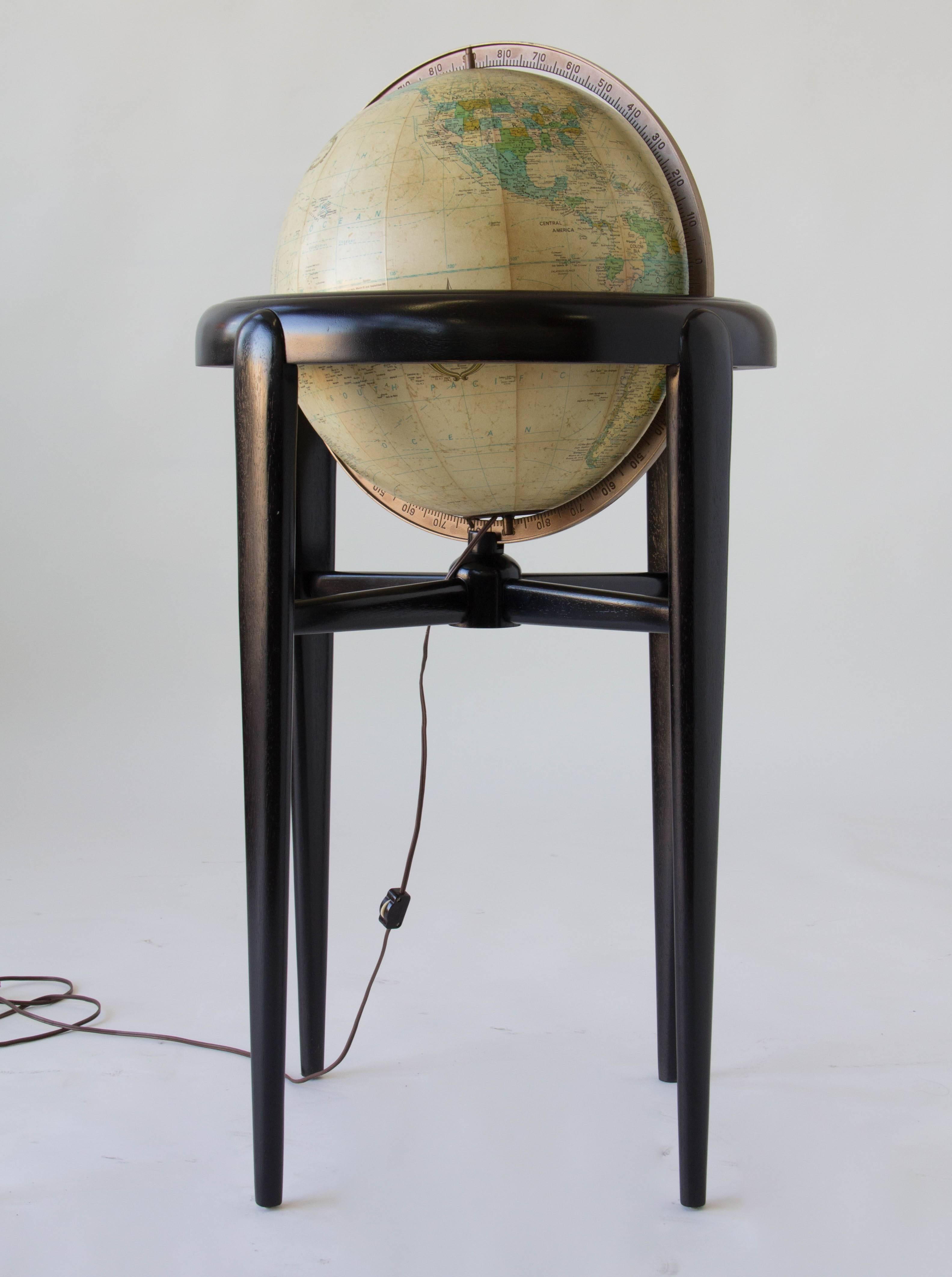 An Heirloom Globe by Replogle in a wooden stand with three tapered legs. The globe spins freely in the stand and can rotate on its vertical and horizontal axes. Plugs in to illuminate. 

Condition: Excellent vintage condition; stand has been