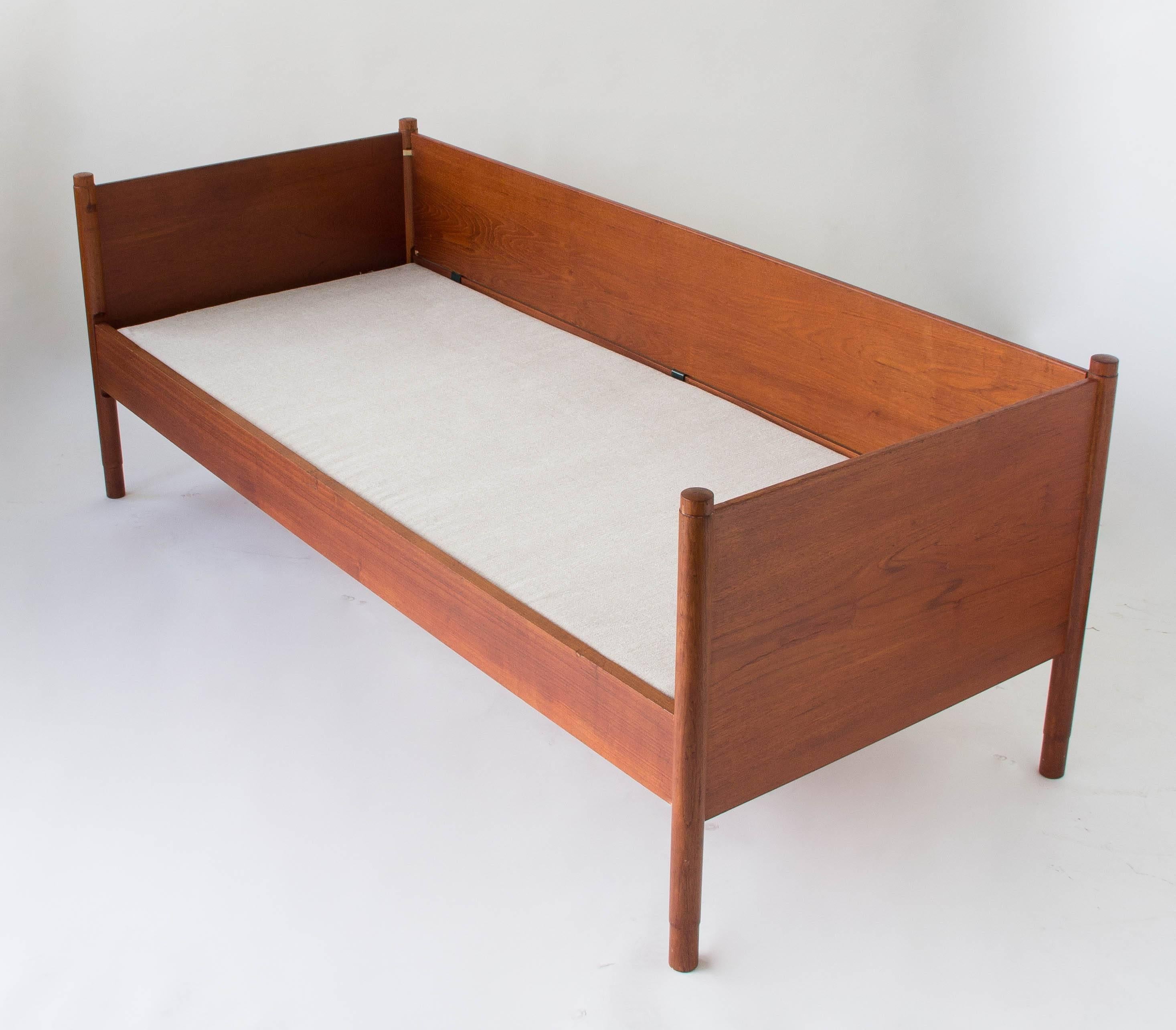 A teak model 136/1 daybed designed in 1951 by Børge Mogensen for Soborg Mobler. The piece has tapered dowel legs with slightly rounded tops. The frame is described by three slim teak panels, fitted to the dowels with proprietary brass hardware. The