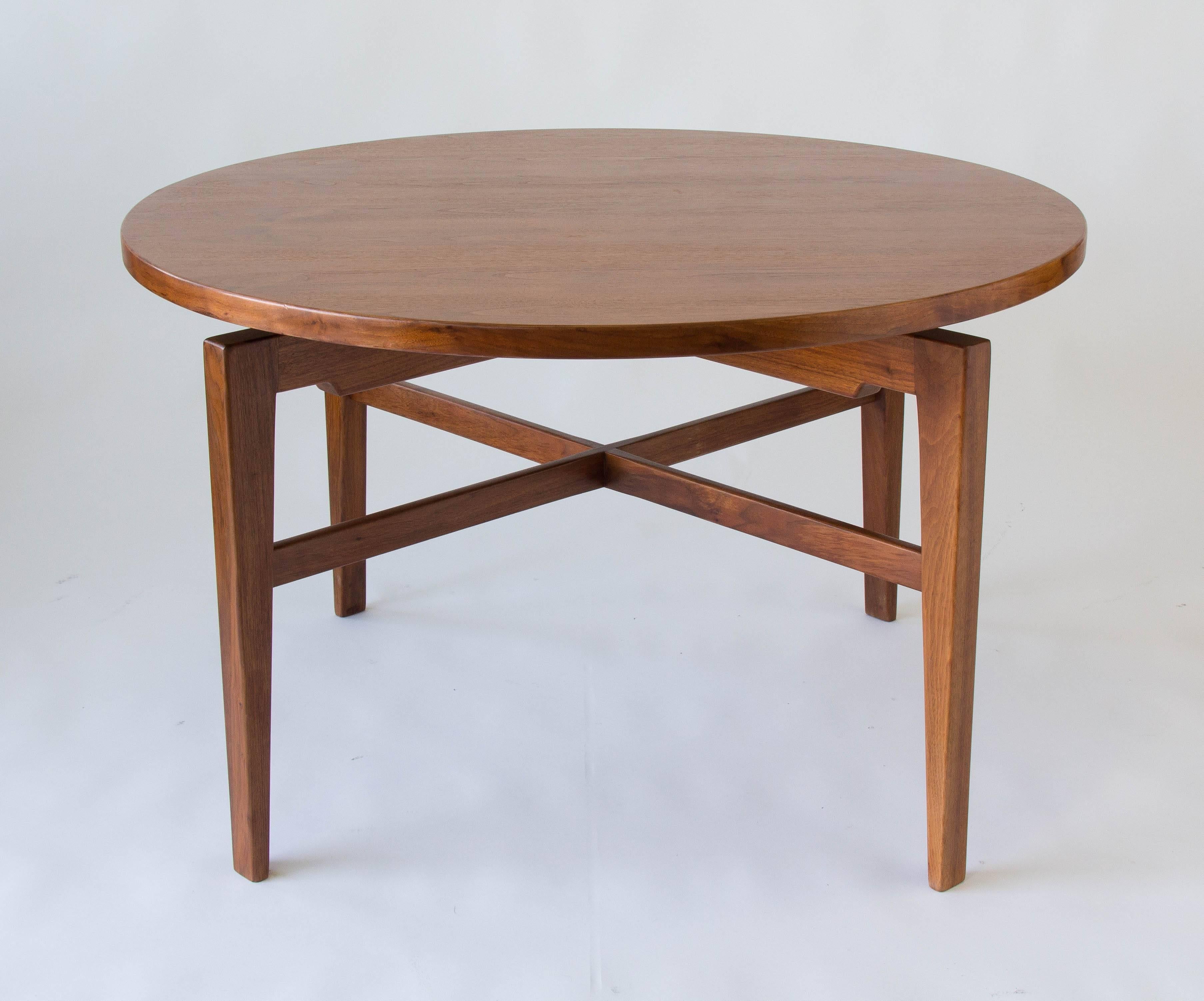 A walnut game or card table by Jens Risom that rotates on a central mechanism for a “Lazy Susan” effect. There is a hidden wheel underneath the table that can be adjusted to increase resistance and act as a brake. The four sculpted legs of the base
