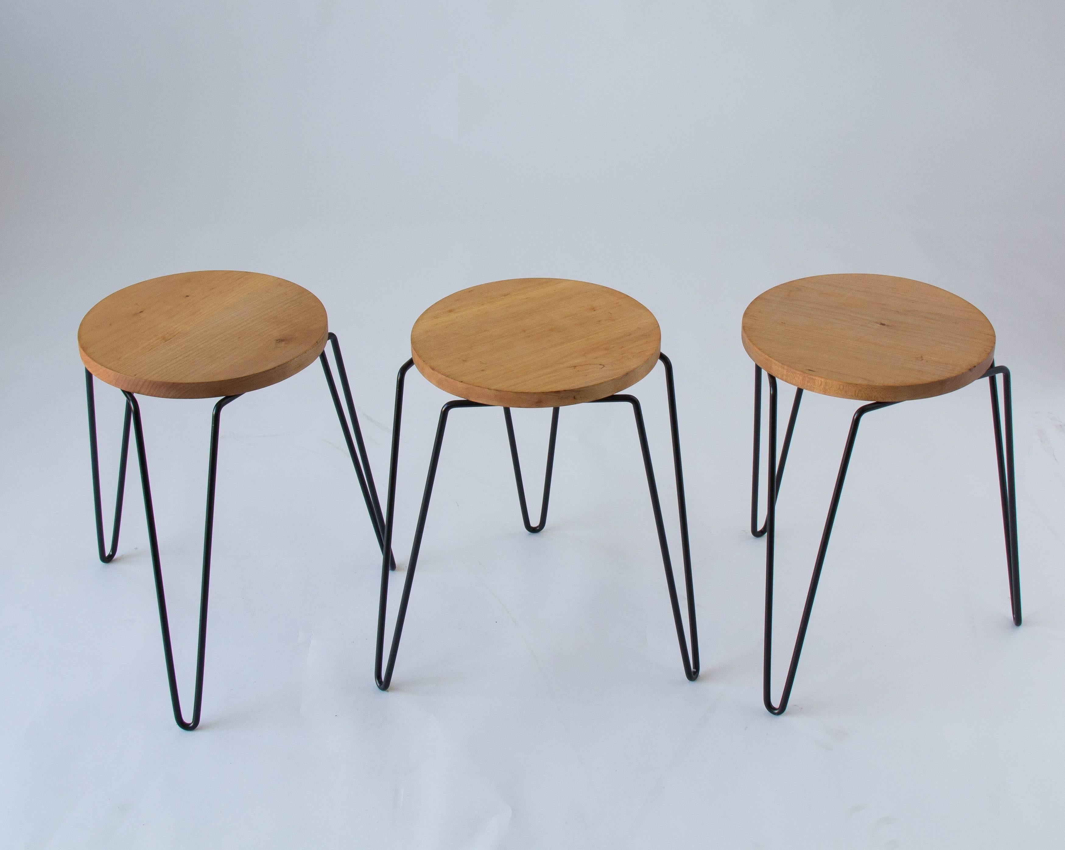 A set of three Florence Knoll-designed stools by Knoll Associates. The No. 75 stool has a round birch seat and wrought iron legs in a ‘hairpin’ style. The stools stack for ease of storage. 

Condition: Excellent restored condition; the seats have