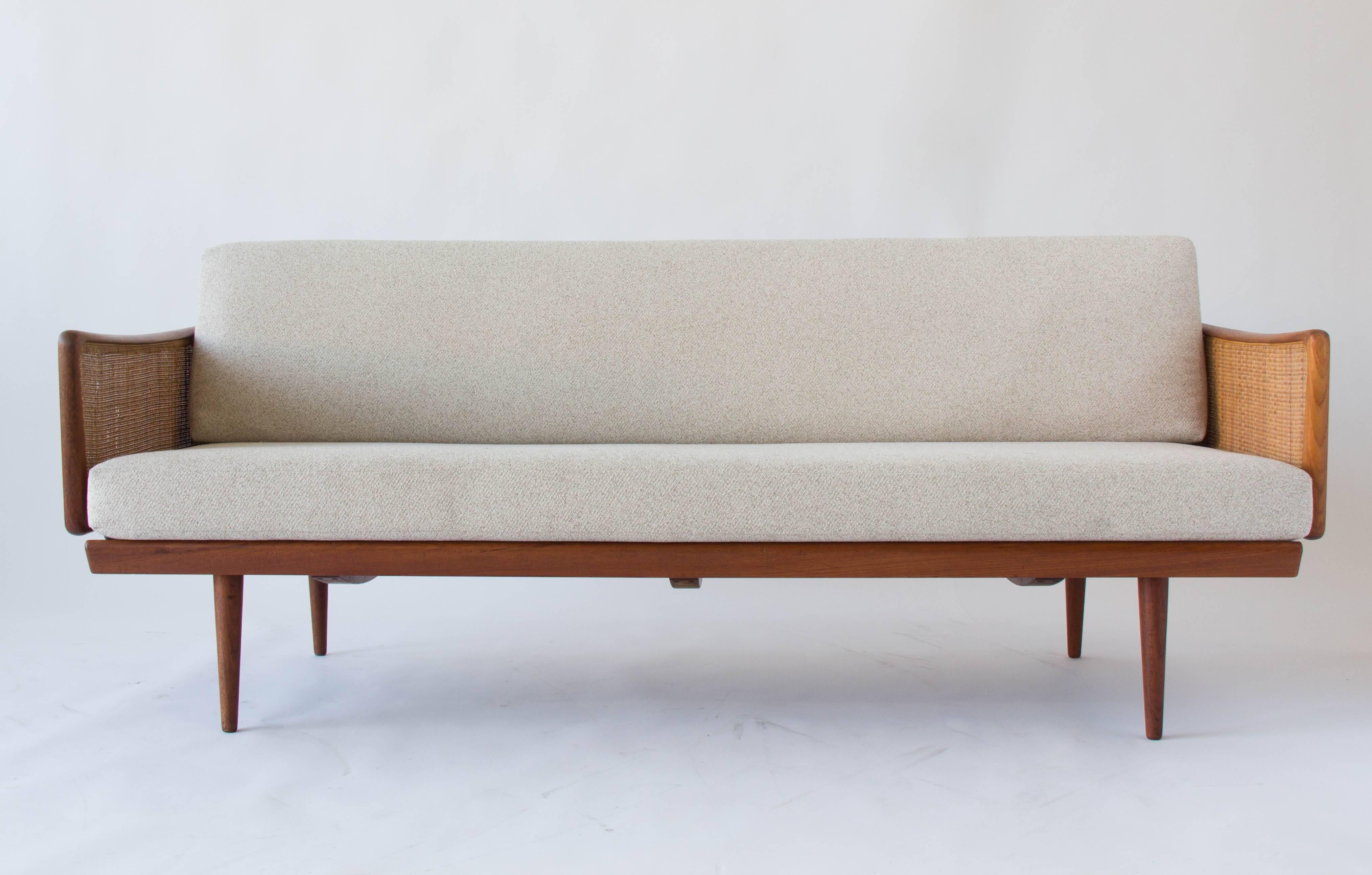 A modestly-sized sofa designed by Peter Hvidt and Orla Mølgaard-Nielsen for John Stuart of New York. The sofa was manufactured in Denmark by France and Daverkosen. The teak frame is fitted with panels of woven cane at the back- and arm-rests, and