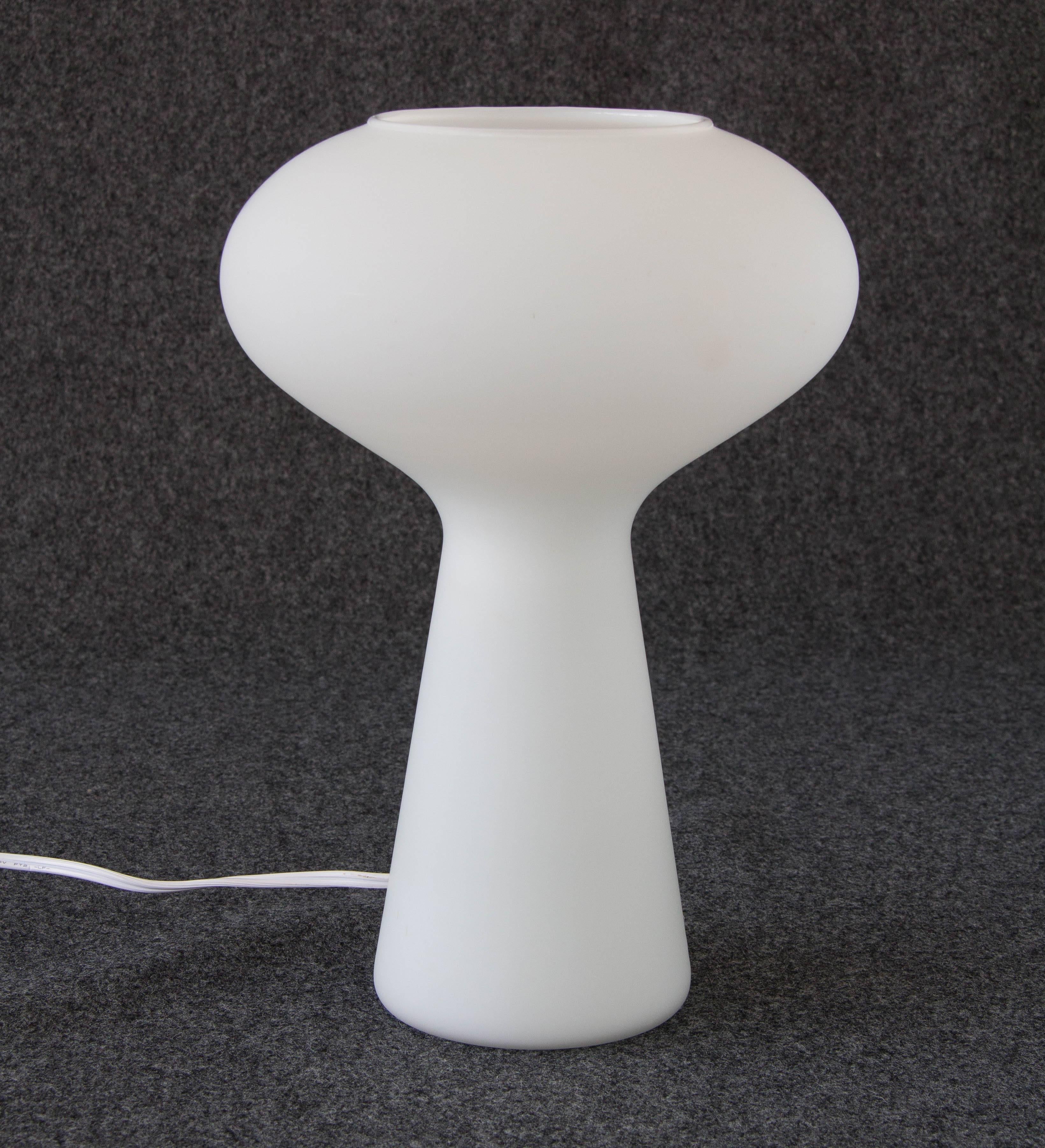 This mushroom lamp emerged in 1954, designed for Finnish glass manufacturer Iitala by Lisa Johansson-Pape, and was marketed by Stockmann-Orno. The lamp has an open top with a biomorphic, curved form, sitting atop a rounded base. The piece is made