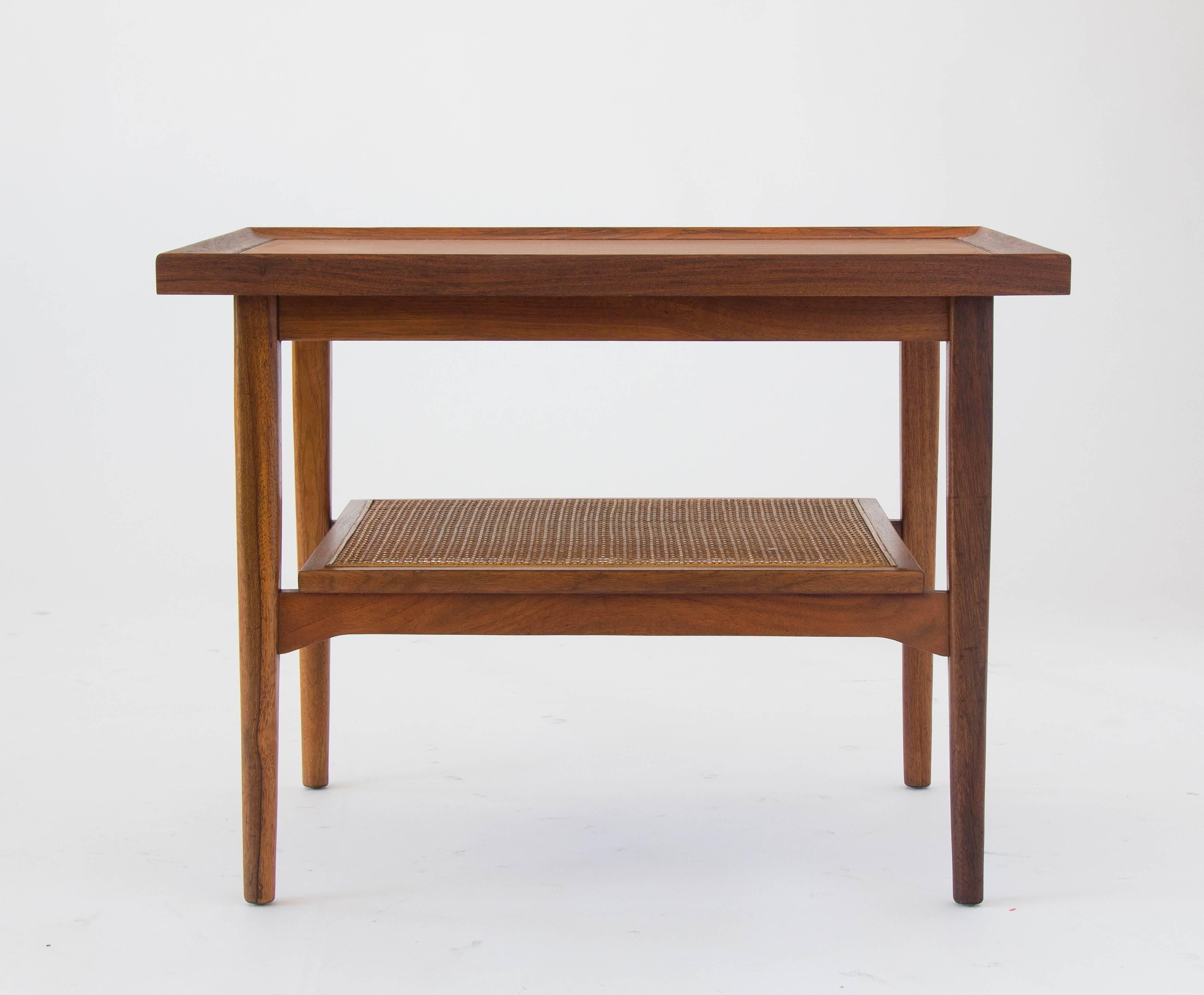 A rectangular side table from Kipp Stewart and Stewart MacDougall’s iconic Declaration collection for Drexel. The walnut tabletop is framed on all sides by end pieces of solid walnut, that create a graduated lip. A smaller shelf with a walnut frame