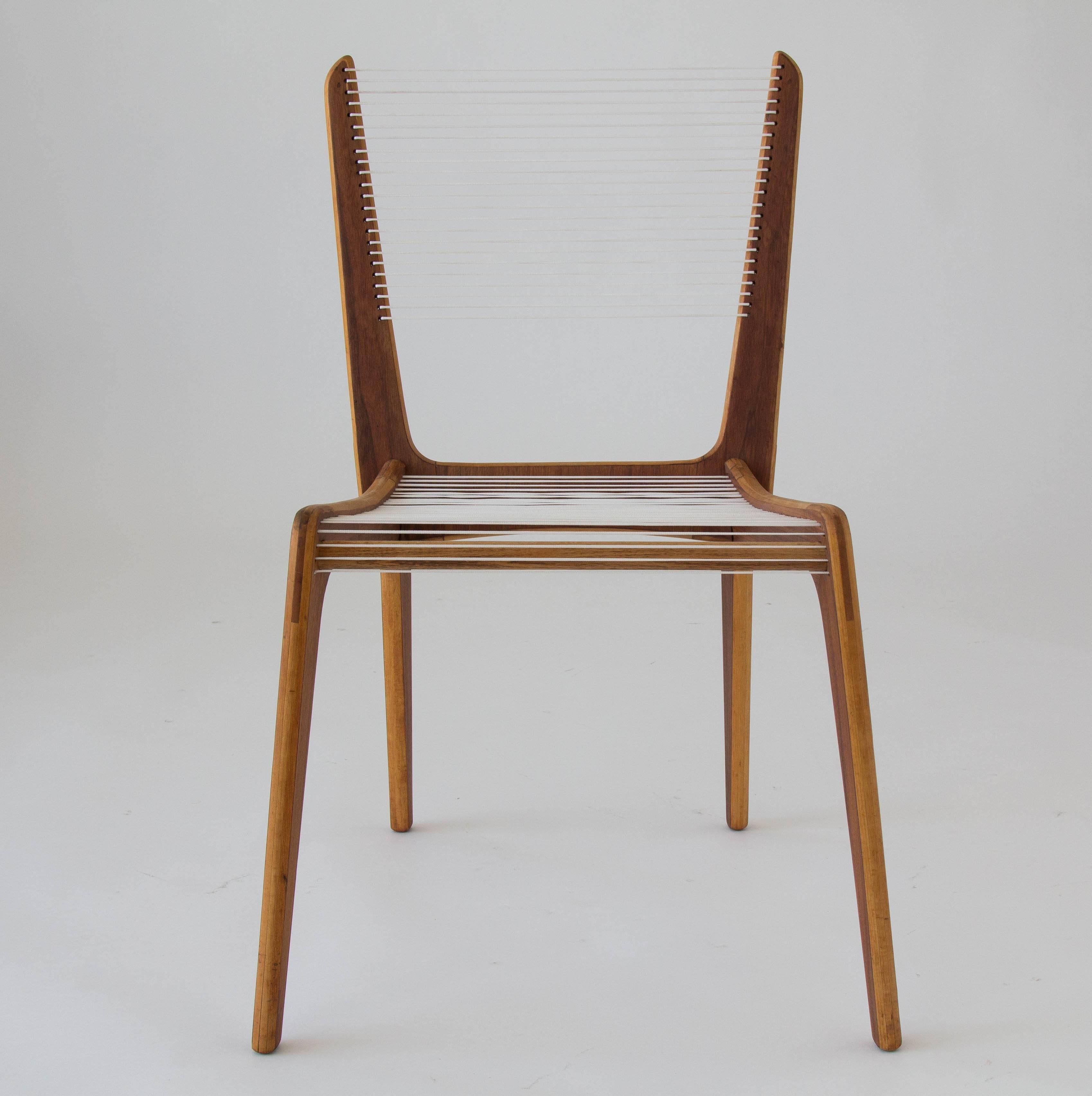 A single accent chair by French Canadian designer Jacques Guillon. Designed in 1953, the deceptively simple design consists of three interlocking wooden pieces - stacked maple faced with a contrasting walnut veneer - joined by a wooden dowel, and