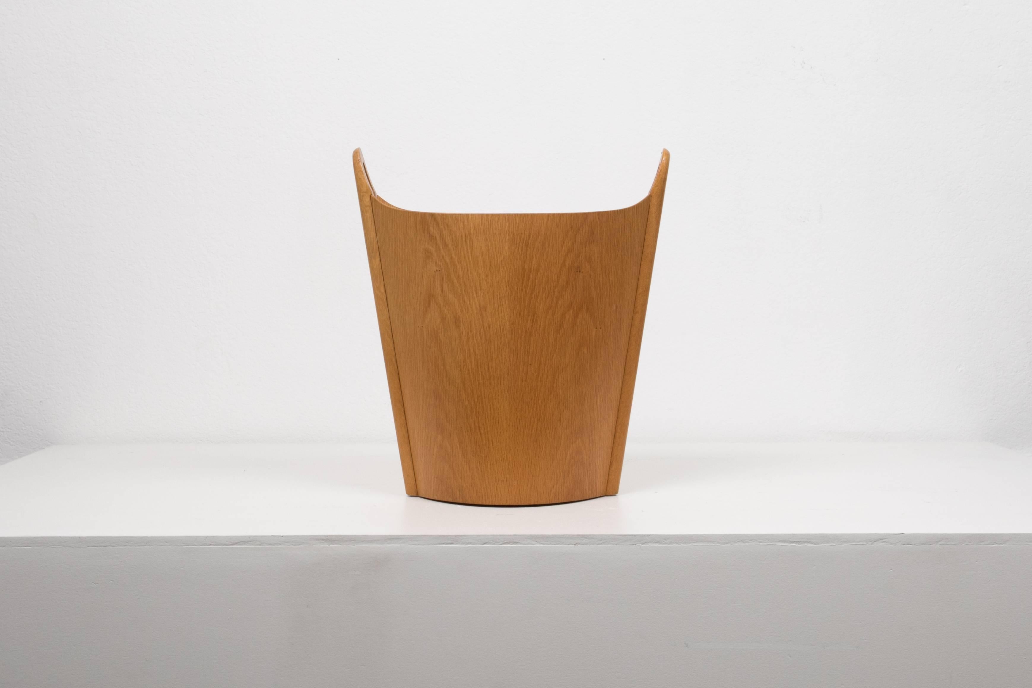 A wastebasket with delicate construction in elegantly patinated oak, designed and produced in Norway by Einar Barnes for P. S. Heggen. The oblong vessel has a ridge of solid oak at either end with a round, integrated handle.

Condition: Good