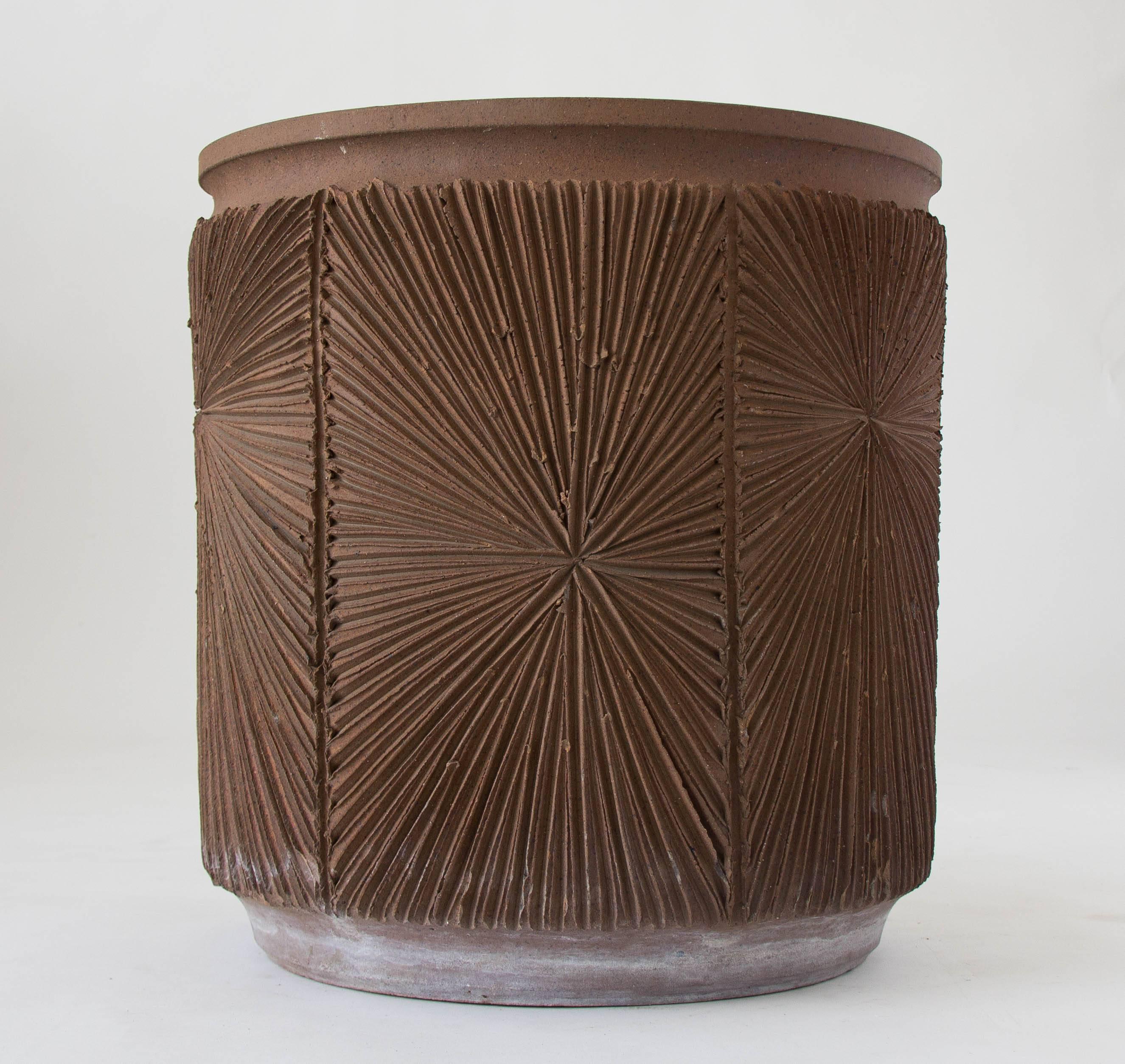 A tall stoneware planter from Robert Maxwell 1970s collaboration Earthgender. The planter has a rounded lip and an incised all-over sunburst pattern and is unglazed. We have an additional planter available in this size with a glazed interior.