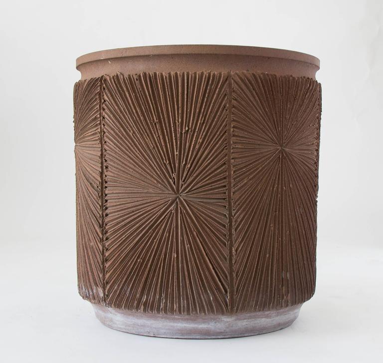 A tall stoneware planter from Robert Maxwell 1970s collaboration Earthgender. The planter has a rounded lip and an incised all-over sunburst pattern and is unglazed. We have two planters available in this size and finish, and the listed price is per