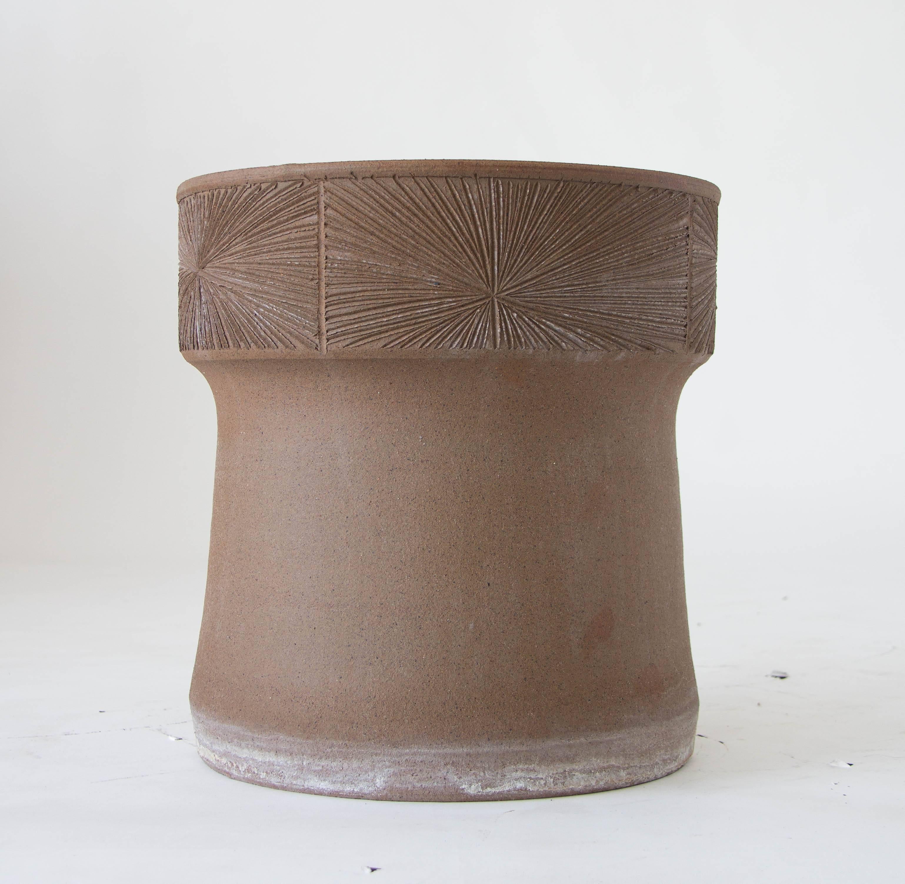 A stoneware planter from David Cressey/Robert Maxwell 1970s collaboration Earthgender. The planter has plain sides flared towards the foot, and a wide lip with an incised sunburst pattern. The interior of the planter is glazed. 

Condition: