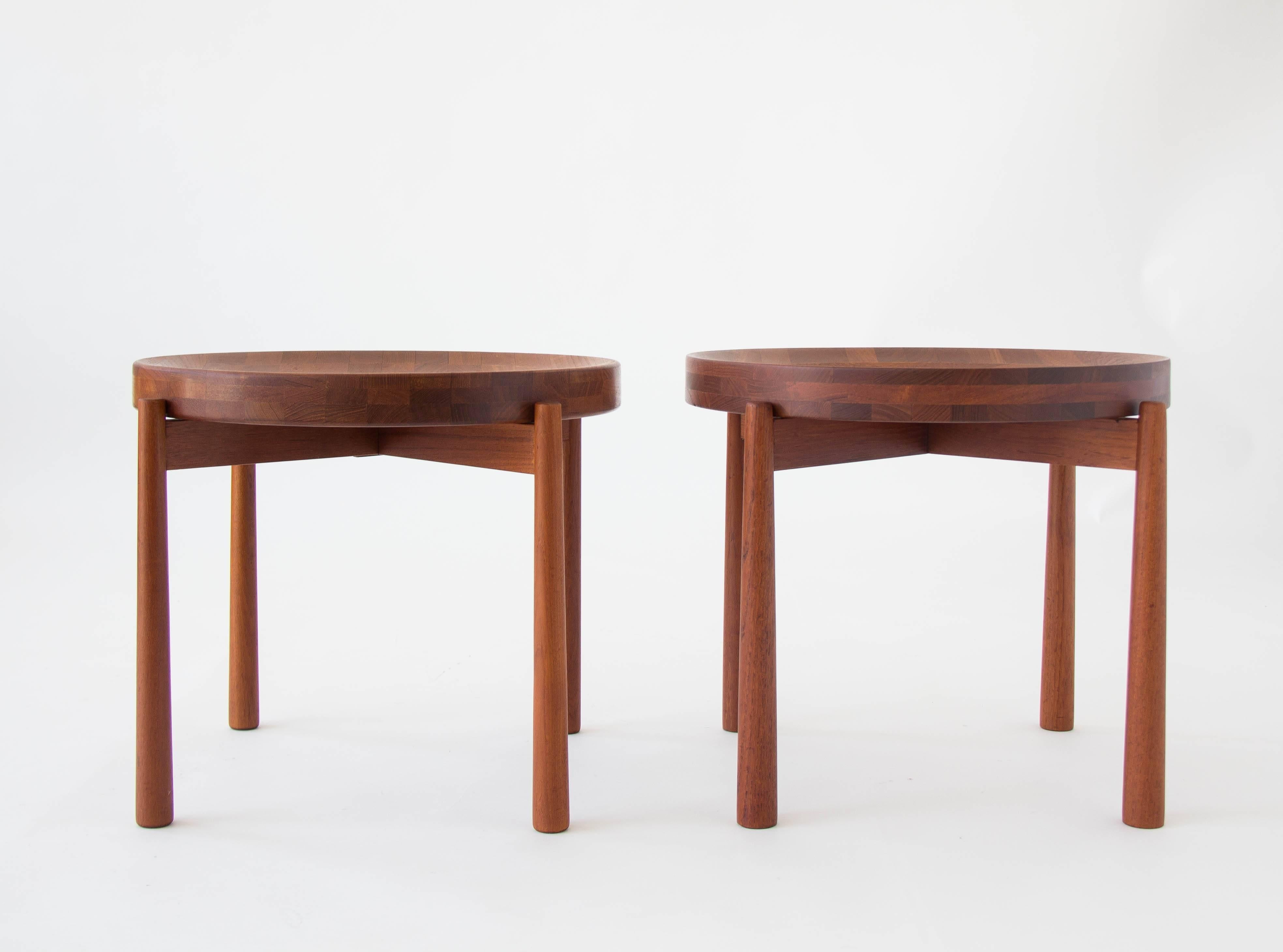 A pair of unique teak side tables. The fully finished top is flat on one side, and concave on the other, and can be removed and flipped according to use. The table stands on four flared legs. Concave surface has a beautiful checkered pattern of
