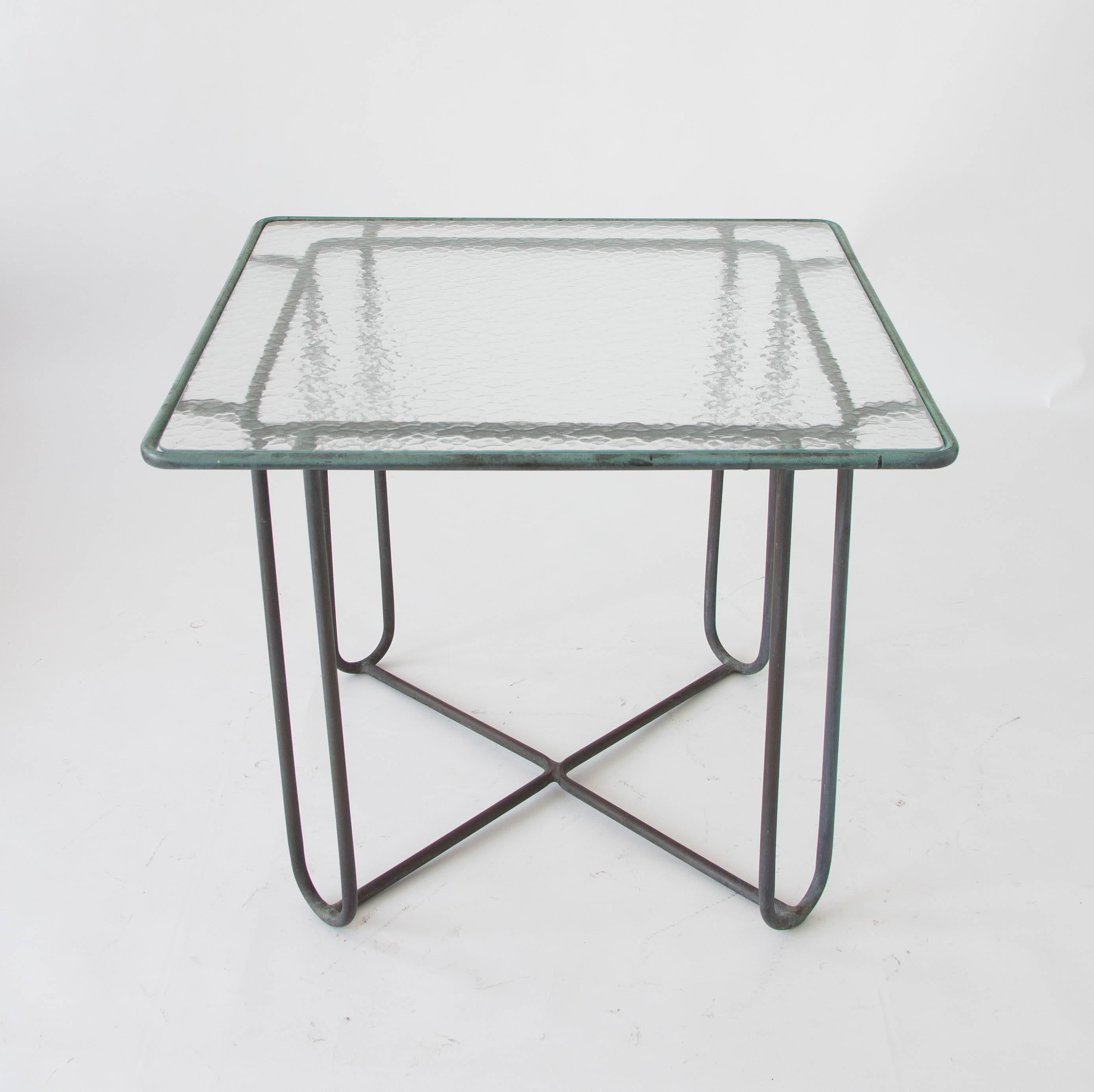 A small patio dining or card table in patinated bronze designed by Walter Lamb and produced by Brown Jordan. The table has a square shape with rounded corners, supported by four hairpin legs in matching bronze. The legs are joined by diagonal