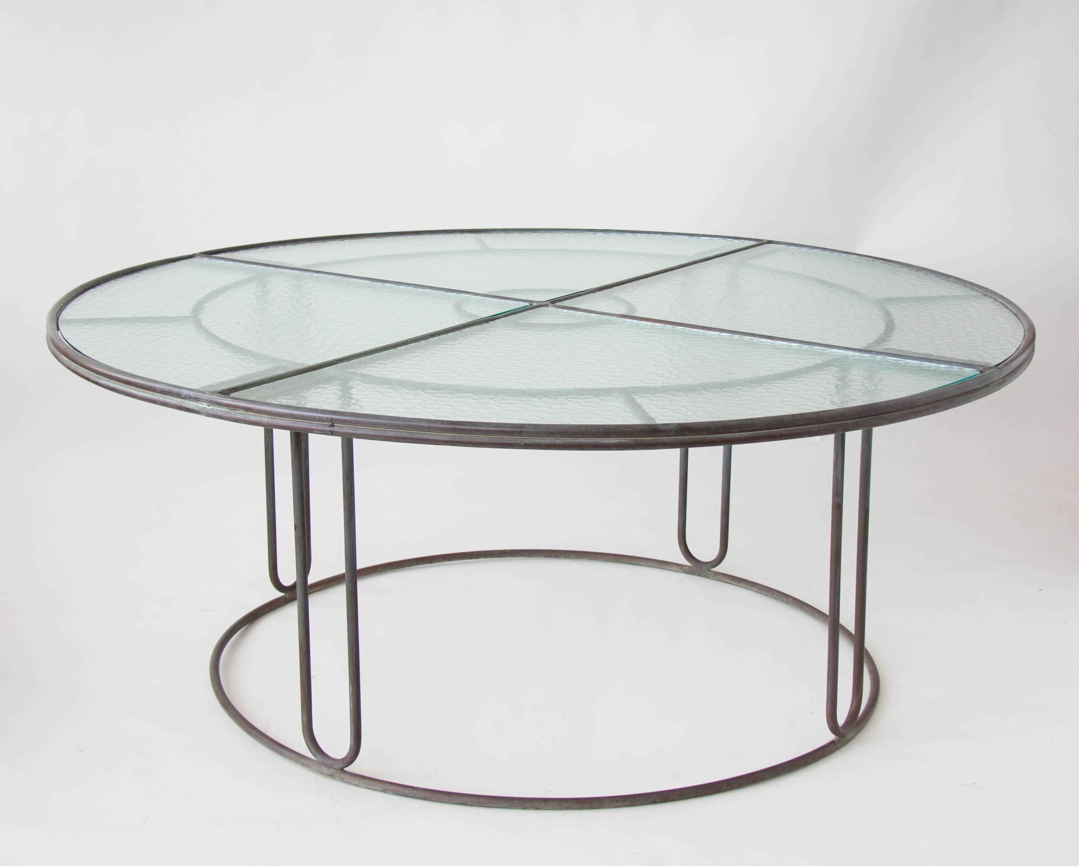 A patio dining table in patinated bronze designed by Walter Lamb and produced by Brown Jordan. The monumental piece has a quartered frame of bronze with two concentric rings and radial supports and a circular bronze base. Hairpin legs join the