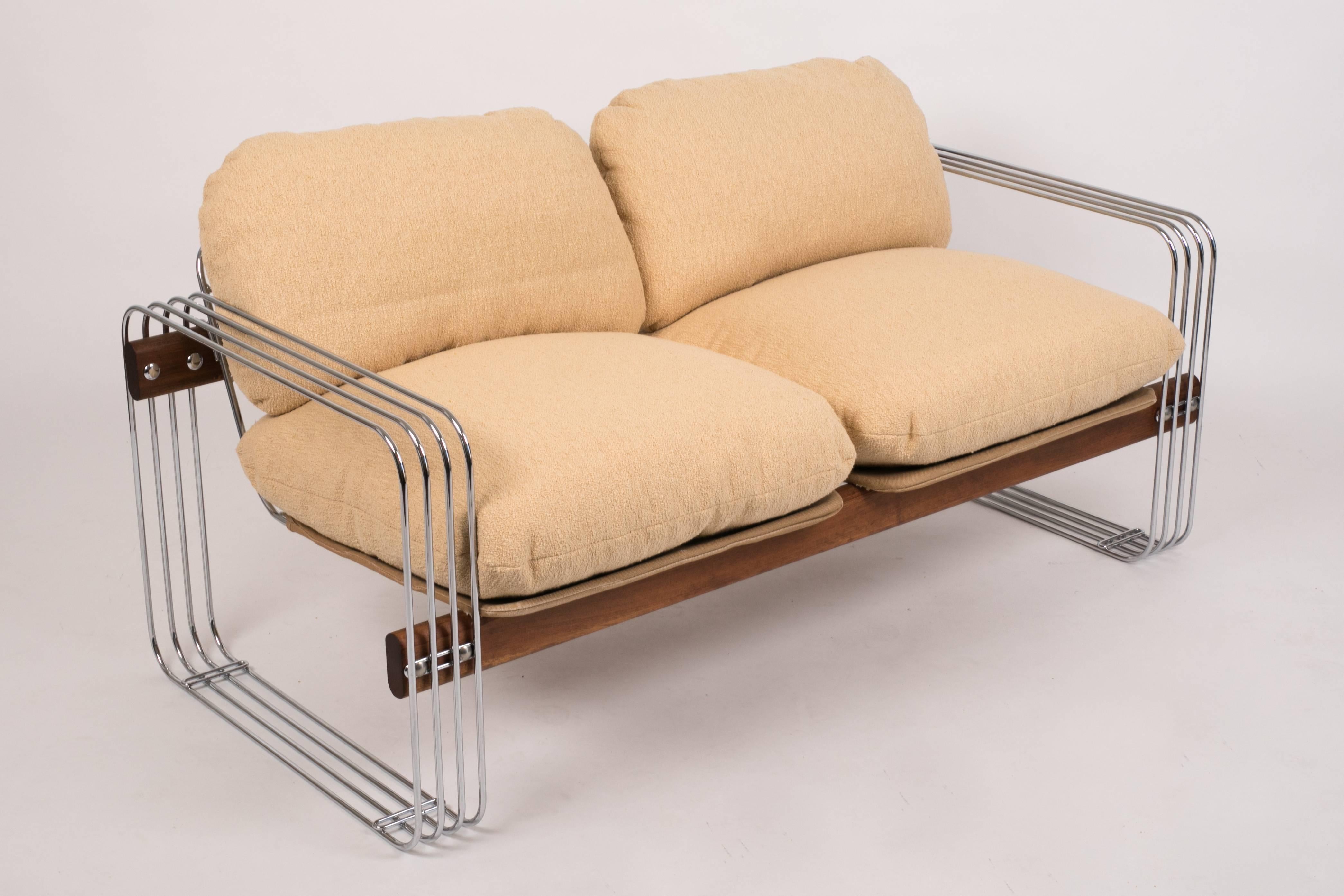 A California-designed loveseat by Heinz Meier for Landes Manufacturing Co. Front and back supports of solid walnut seem to float in a skeletal frame of tubular chrome. Soft-sided cushions in a sand beige bouclé describe the body of the piece.