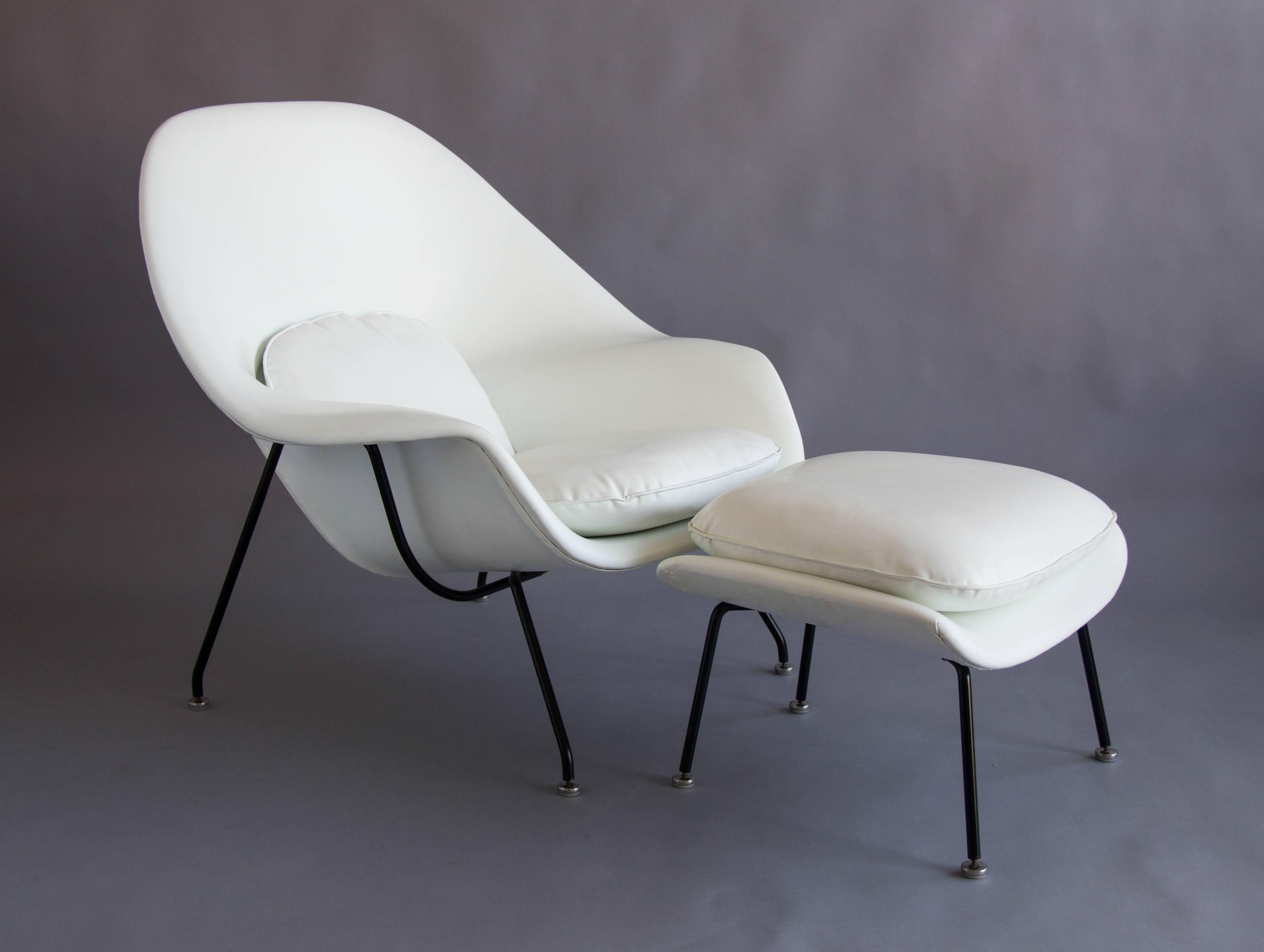 The iconic womb chair by Eero Saarinen for Knoll has a molded fiberglass shell and deceptively slender, minimal cushions, and sits atop a steel frame with angled legs. This 1960s example has the original white vinyl upholstery and black finish on