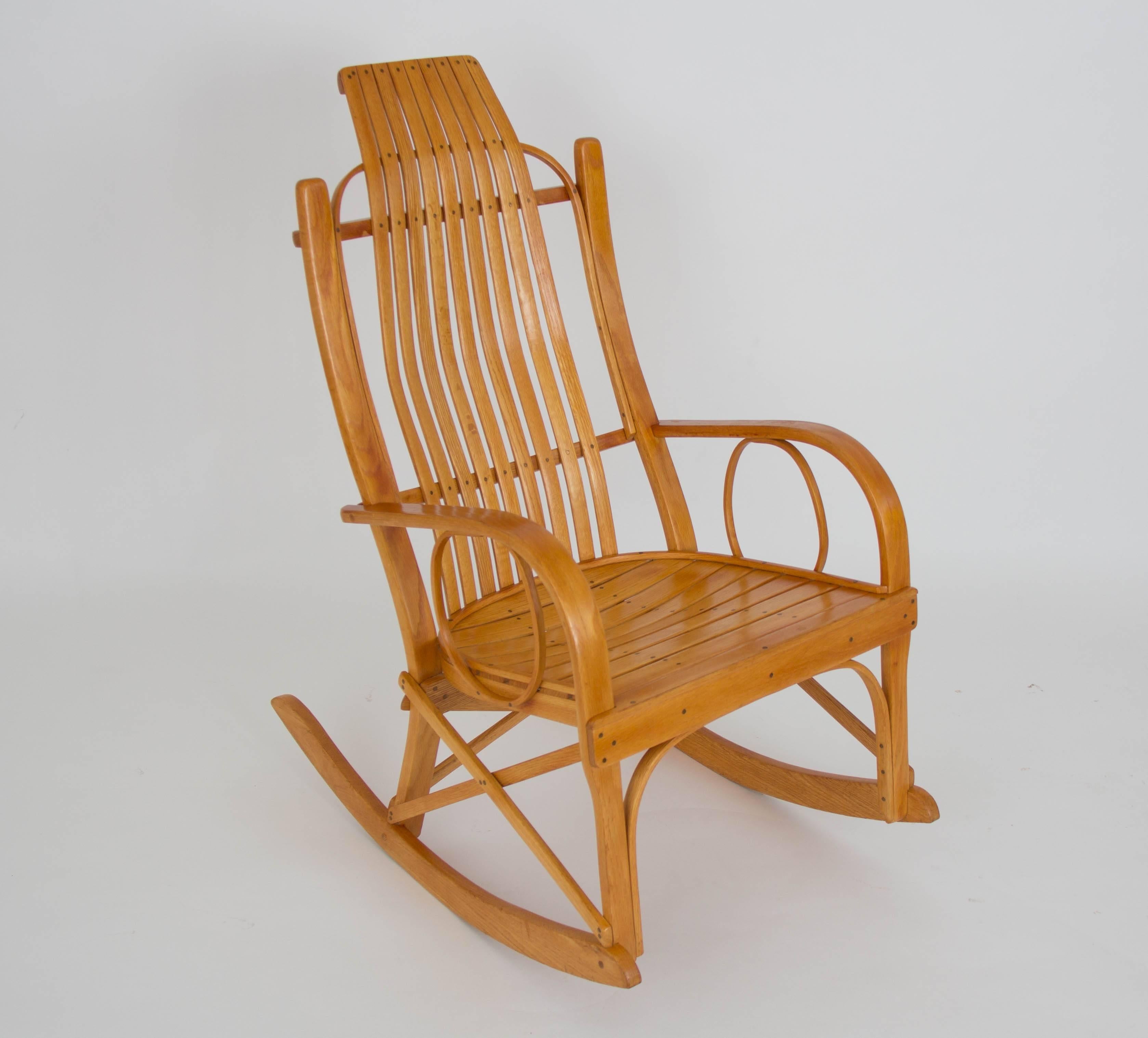 A handcrafted rocking chair in the style of Amish bentwood pieces. This example is made of oak slats laid close together to form the seat and backrest, and concentric runners of bent oak that form the arms and rockers. A small notation beneath the