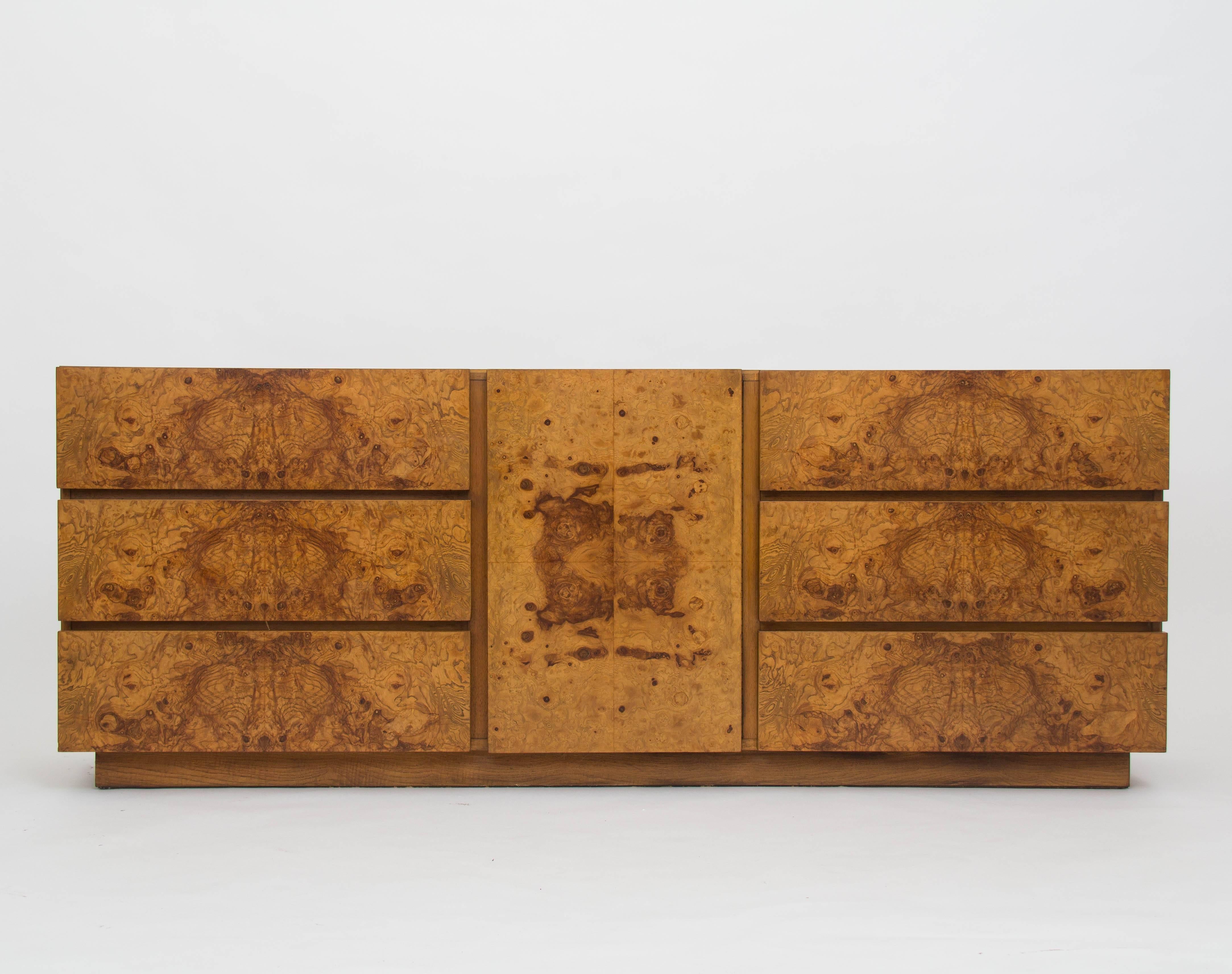 From Lane's 1970s collaboration with Milo Baughman, this nine-drawer credenza or dresser has a case of mahogany, and six drawers with olive burl panelling. A center cabinet with a matching door opens on three additional smaller drawers. The piece
