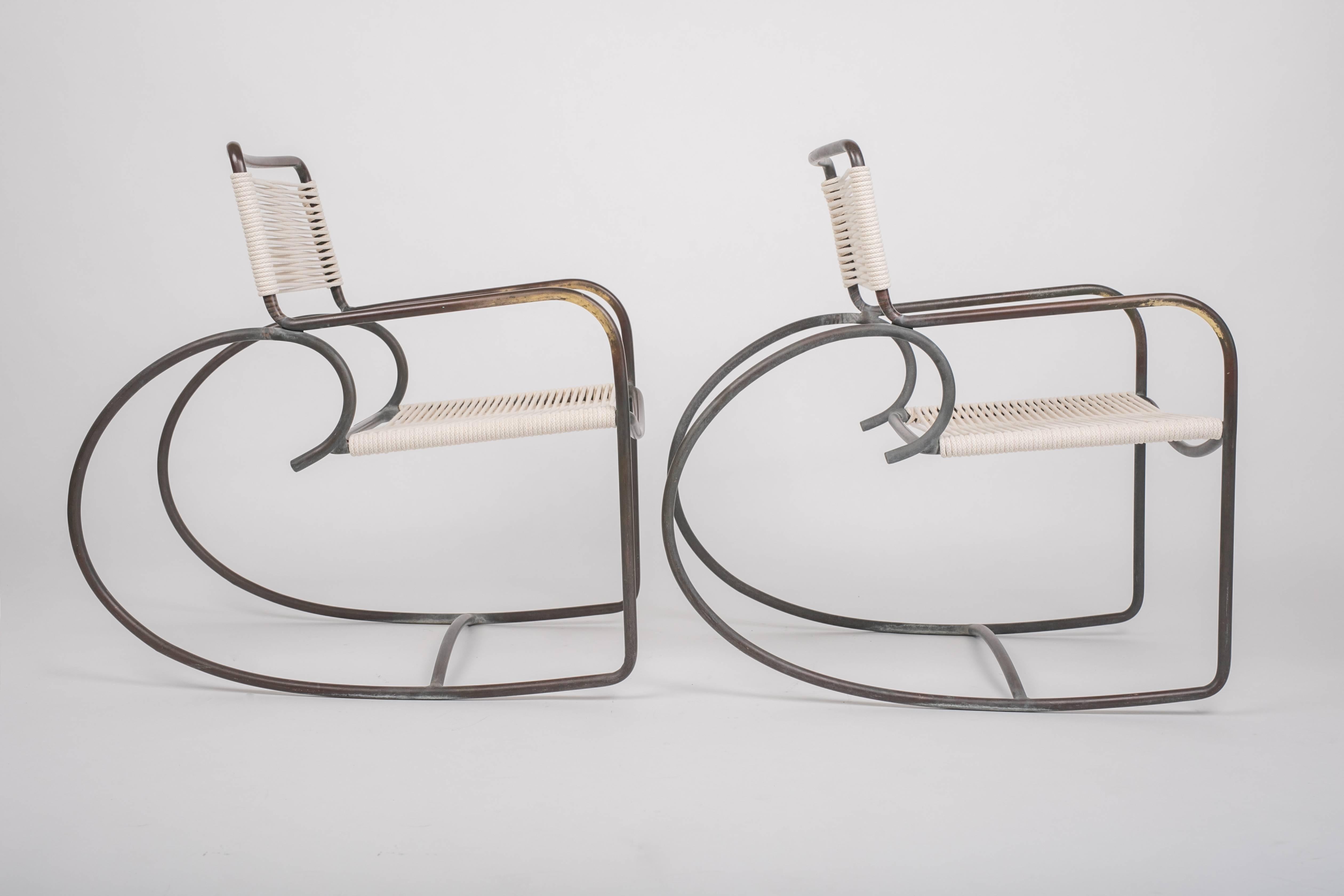 A pair of bronze rocking chairs designed by Walter Lamb and produced by Brown Jordan. The chairs have a sculptural shape, with a single formation of tubular bronze forms the backrest, arms, and exaggerated round runners. The back and seat are strung