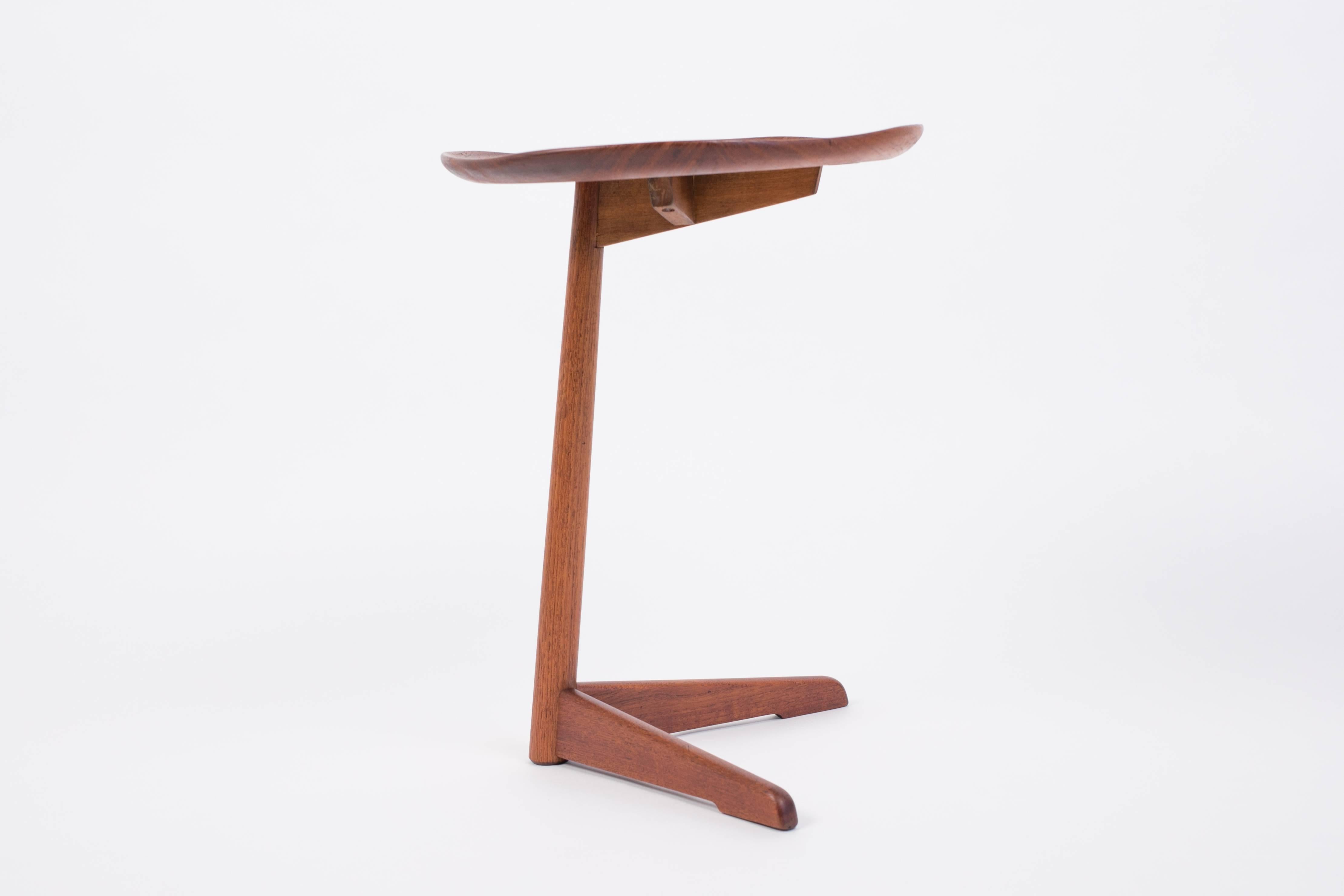 A Norwegian modern side table in solid teak with a cantilevered design and an irregular, fluted tabletop edge. The table has a forked base connected to the tabletop via a turned teak post. Designed and produced for Steen & Strøm’s Møbelfabrikk of