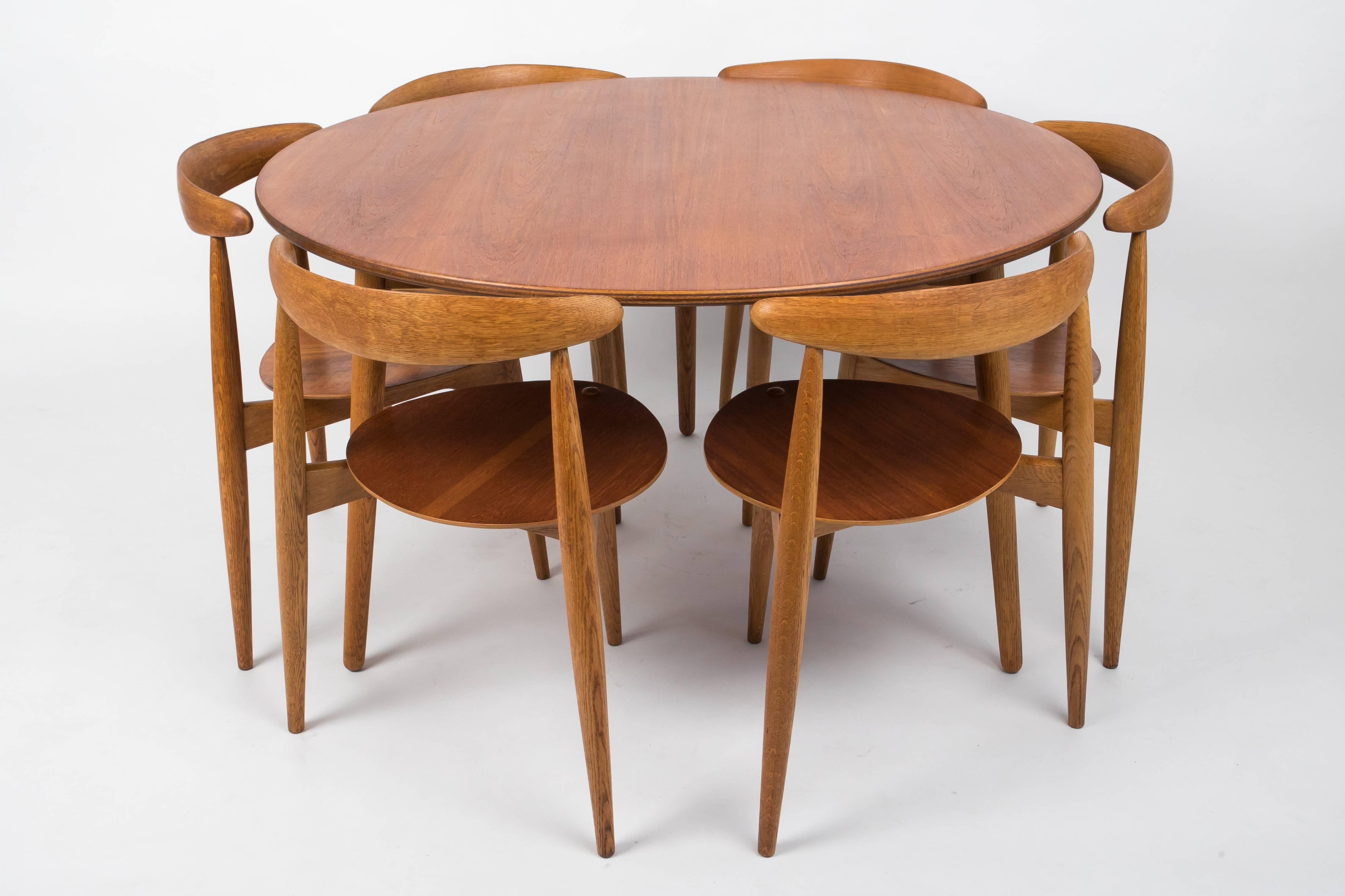 Hans Wegner’s space-efficient dining set for Fritz Hansen in 1952 comprises a round table with three legs and six three-legged chairs with roughly heart-shaped seats. The unique shapes of the seats and the tripod legs of the table allow all seating