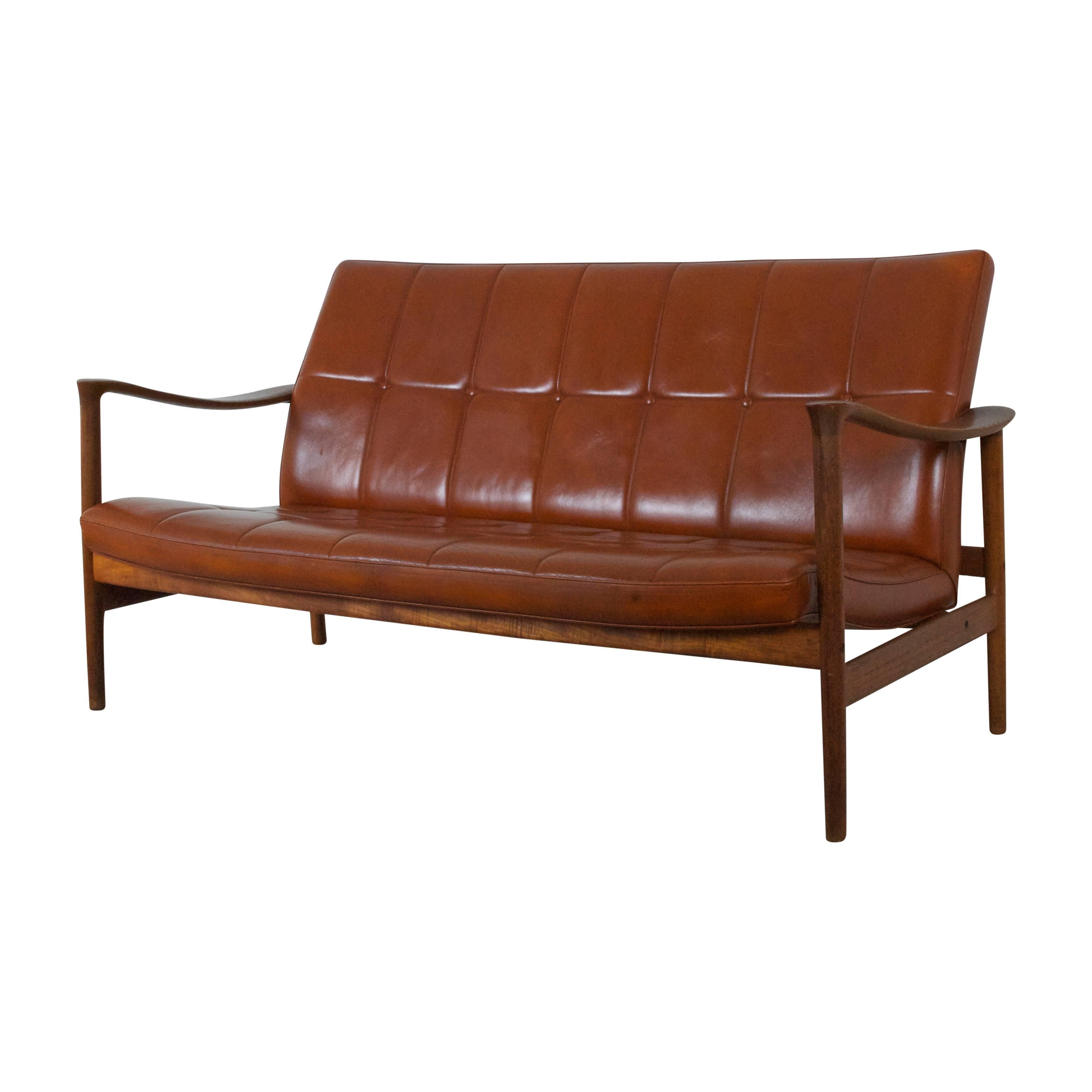 Torbjørn Afdal with Bruksbo design Office two seater settee Model Winston for Nesjestranda Norway 1963. Teak frame and cognac colored leather seat with buttons. 
