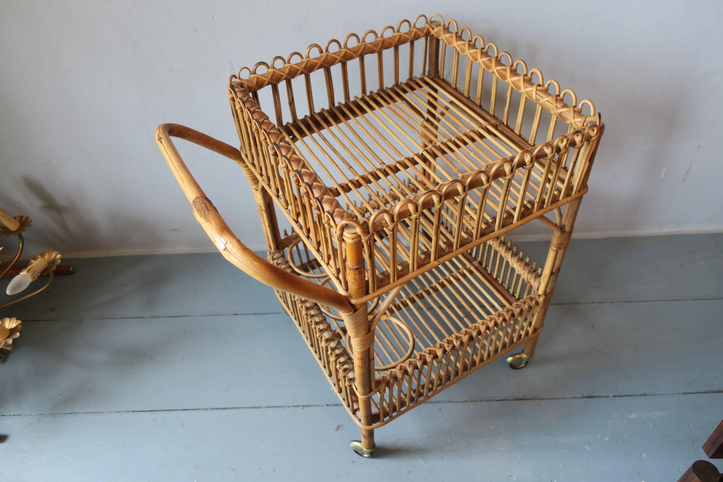 Vintage bamboo bar cart with bottle holders and brass wheels.