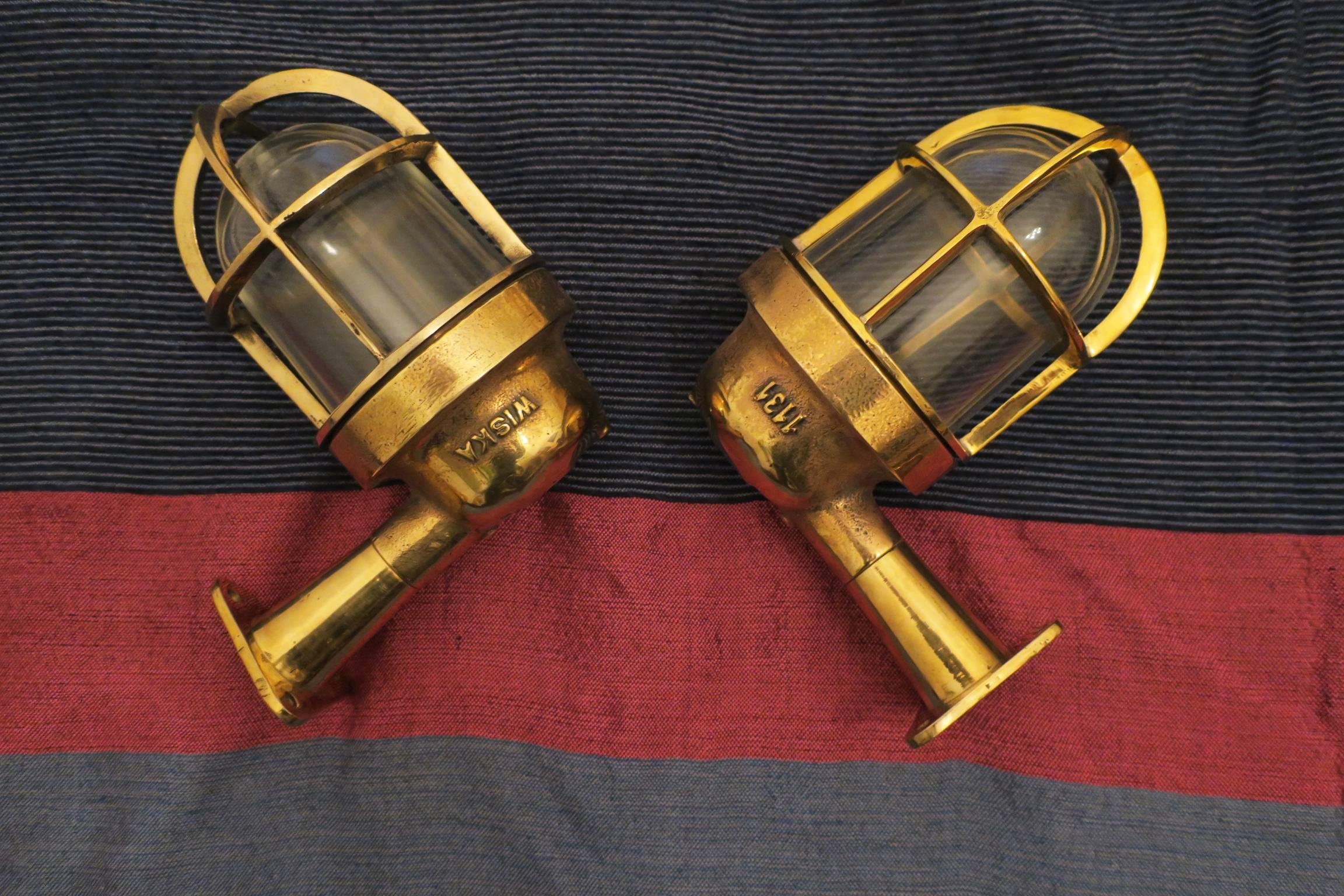 A pair of ships lights or sconces in brass and glass.

The sconces take standard size bulbs with 'bayonet' sockets which are available in many US electrical stores, for example at Canal Hardware Company, 305 Canal Street, NYC:

