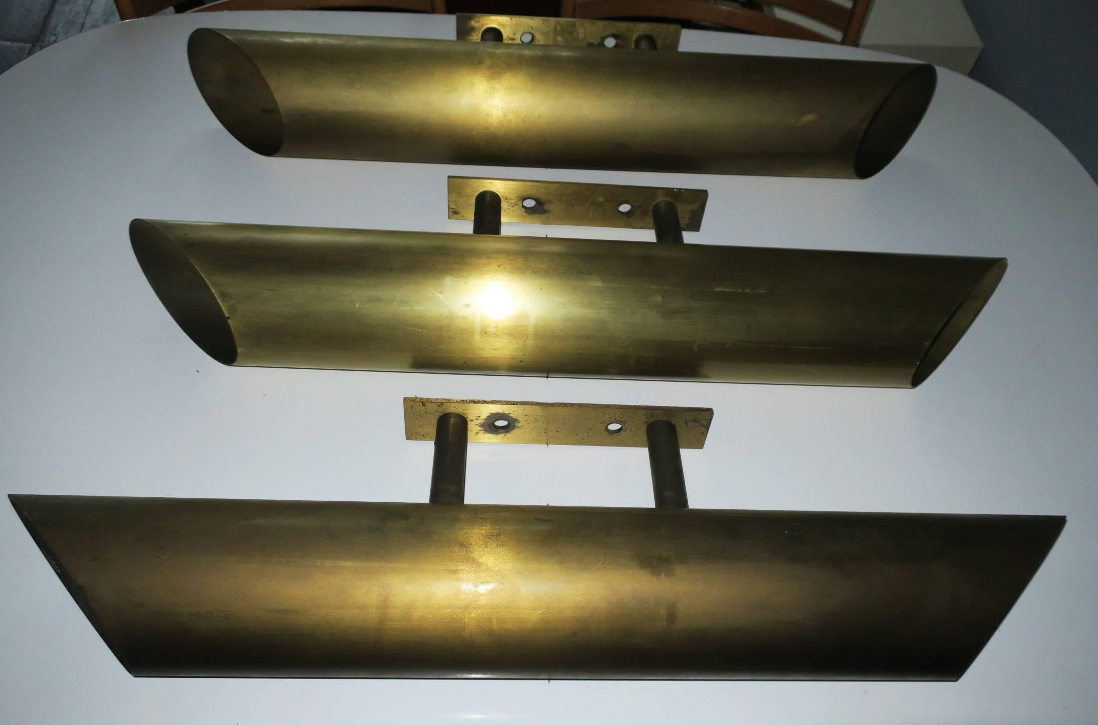 Set of three large solid brass sconces from an old cinema, with an economical design reminiscent of the Bauhaus movement, 1930s-1950s.
The sconces have a light source at each end and thick screw-in glasses to protect the bulbs.
They could be used as