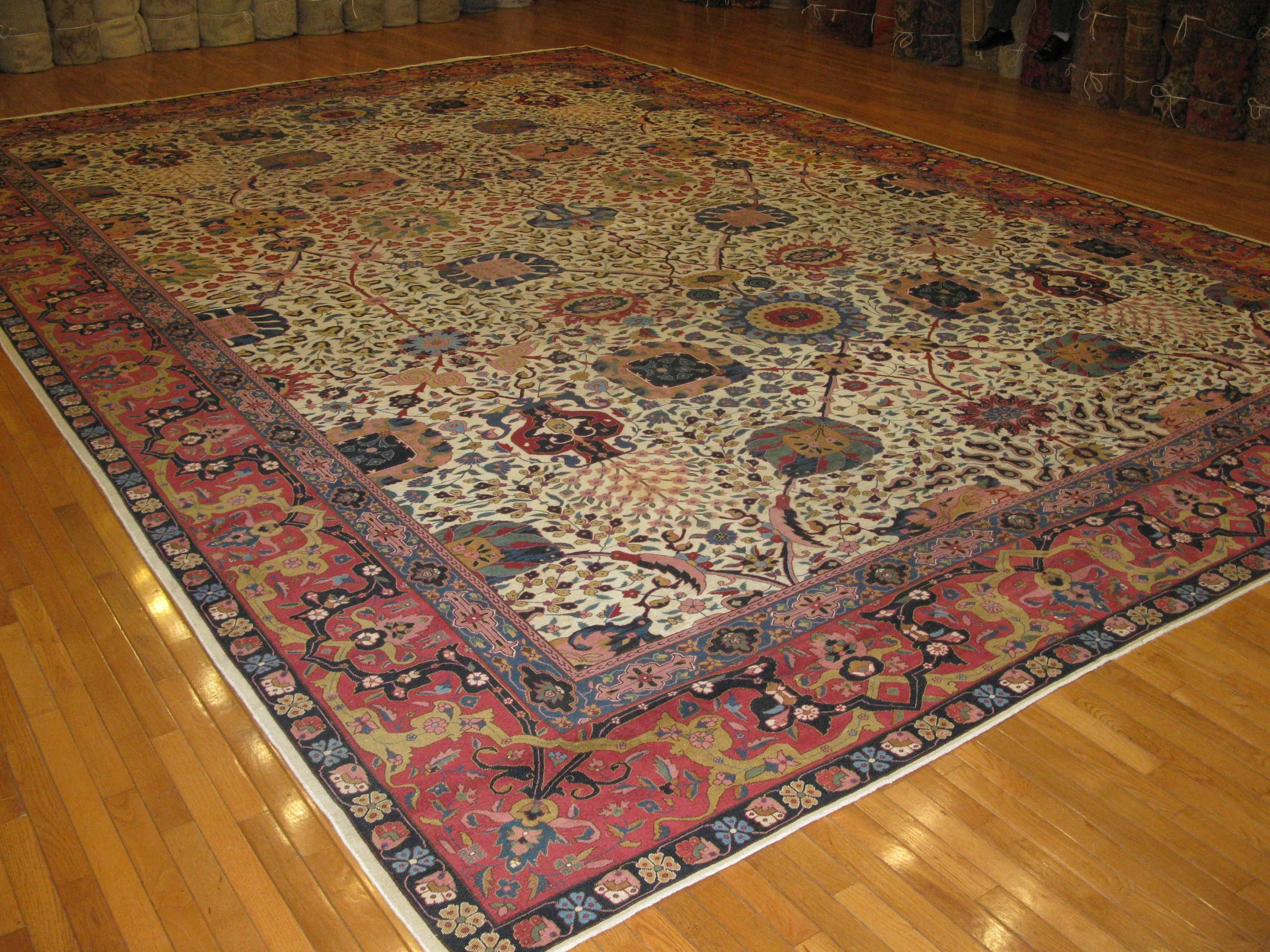 A fabulous large antique hand-knotted Indian Agra inspired by 17th century Persian Tabriz rugs. The rug has beautiful all-over floral pattern on an ivory field and red border. It is in very good shape.