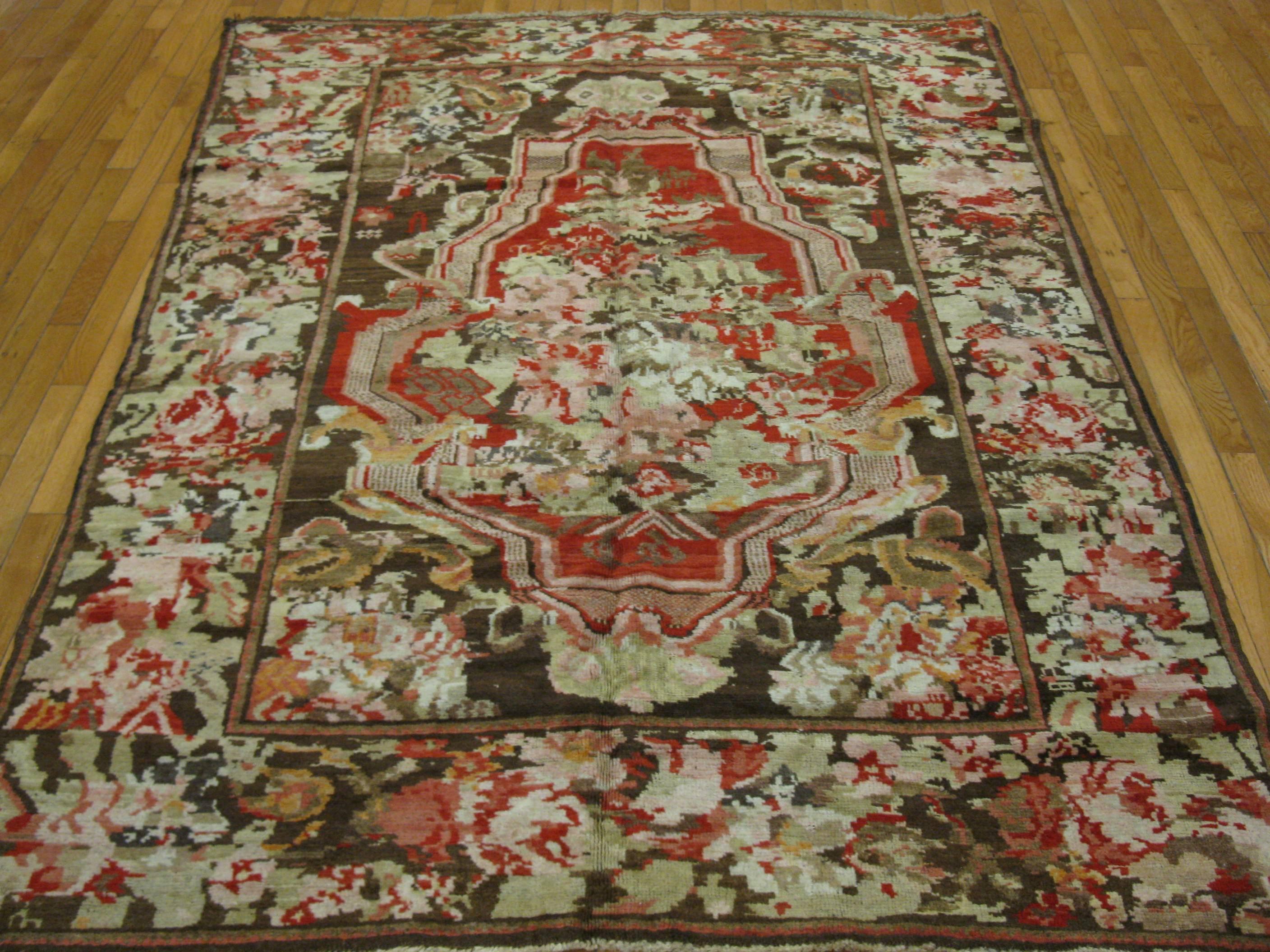 This is a beautiful small hand-knotted antique Karabaq rug from the Caucuses. It has rich natural dye colors with a country French style design. The rug measures 5' 4