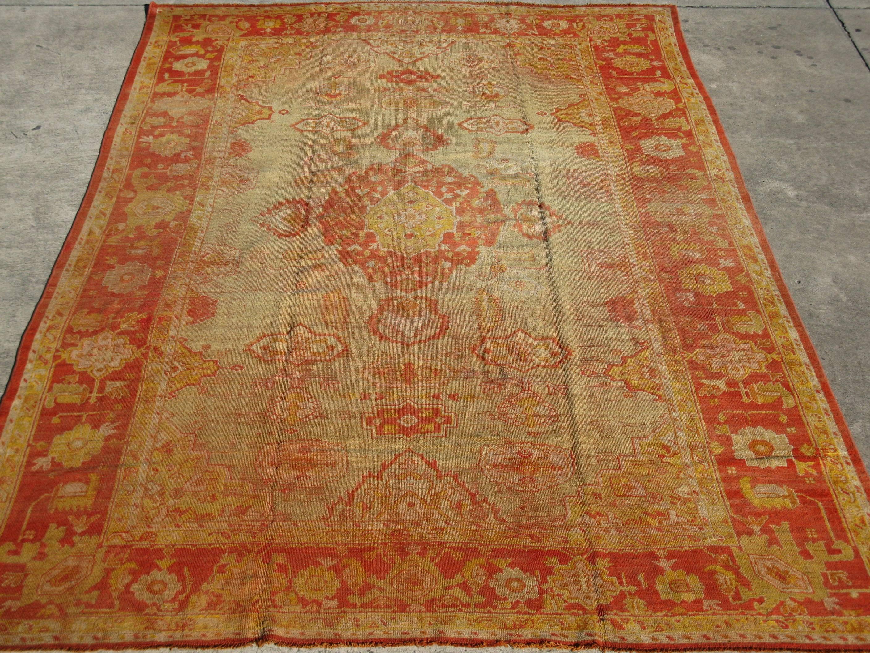This is a late 19th century antique room size Turkish Oushak rug with rich red color border and pale green field. It measures 9' x 13' 7'' and in very good condition.