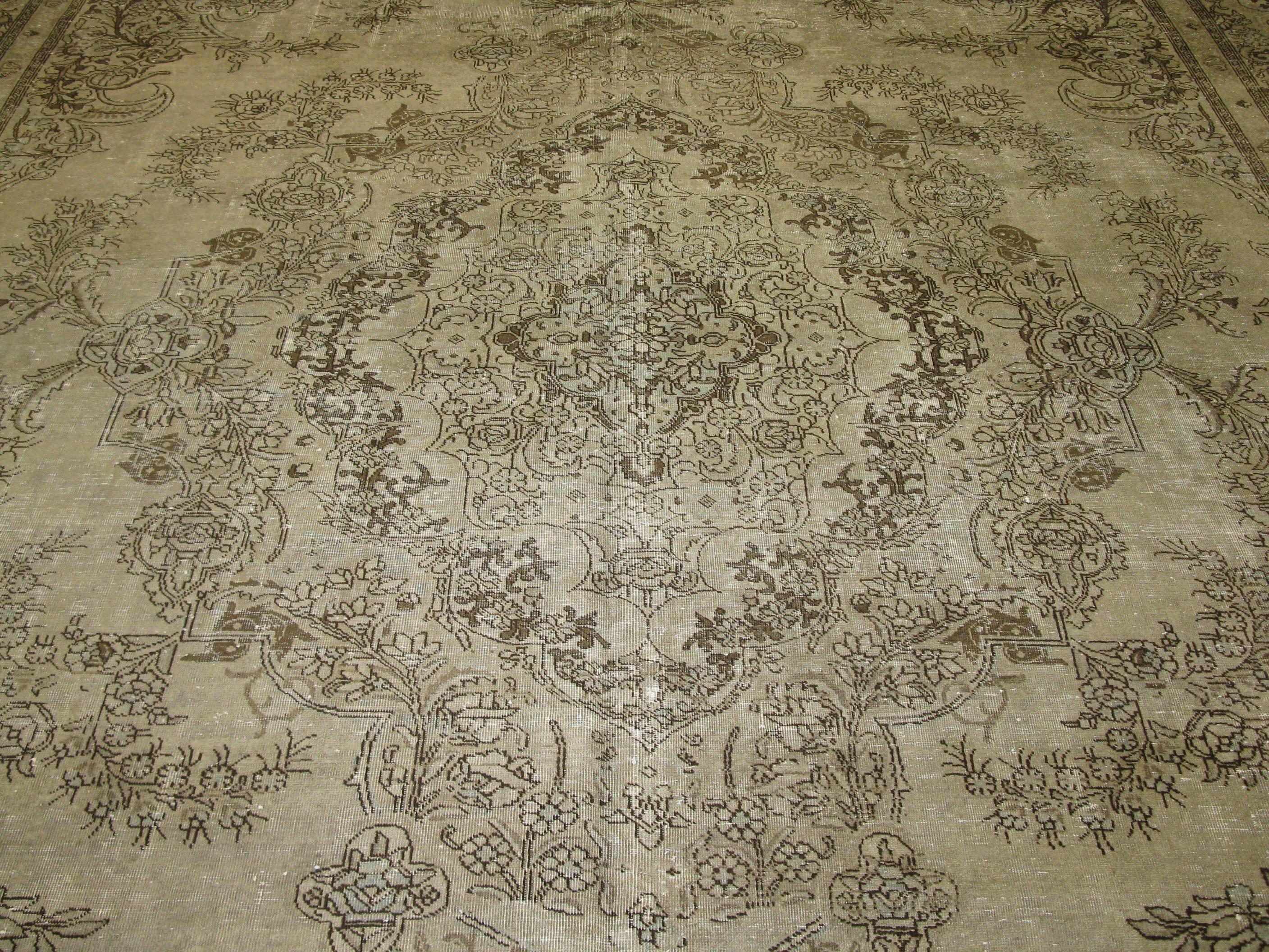 This is a large antique distressed texture Persian Tabriz rug. It has a soft pattern in a neutral antique washed color combination. The rug in good shape and measures 11' x 18'.