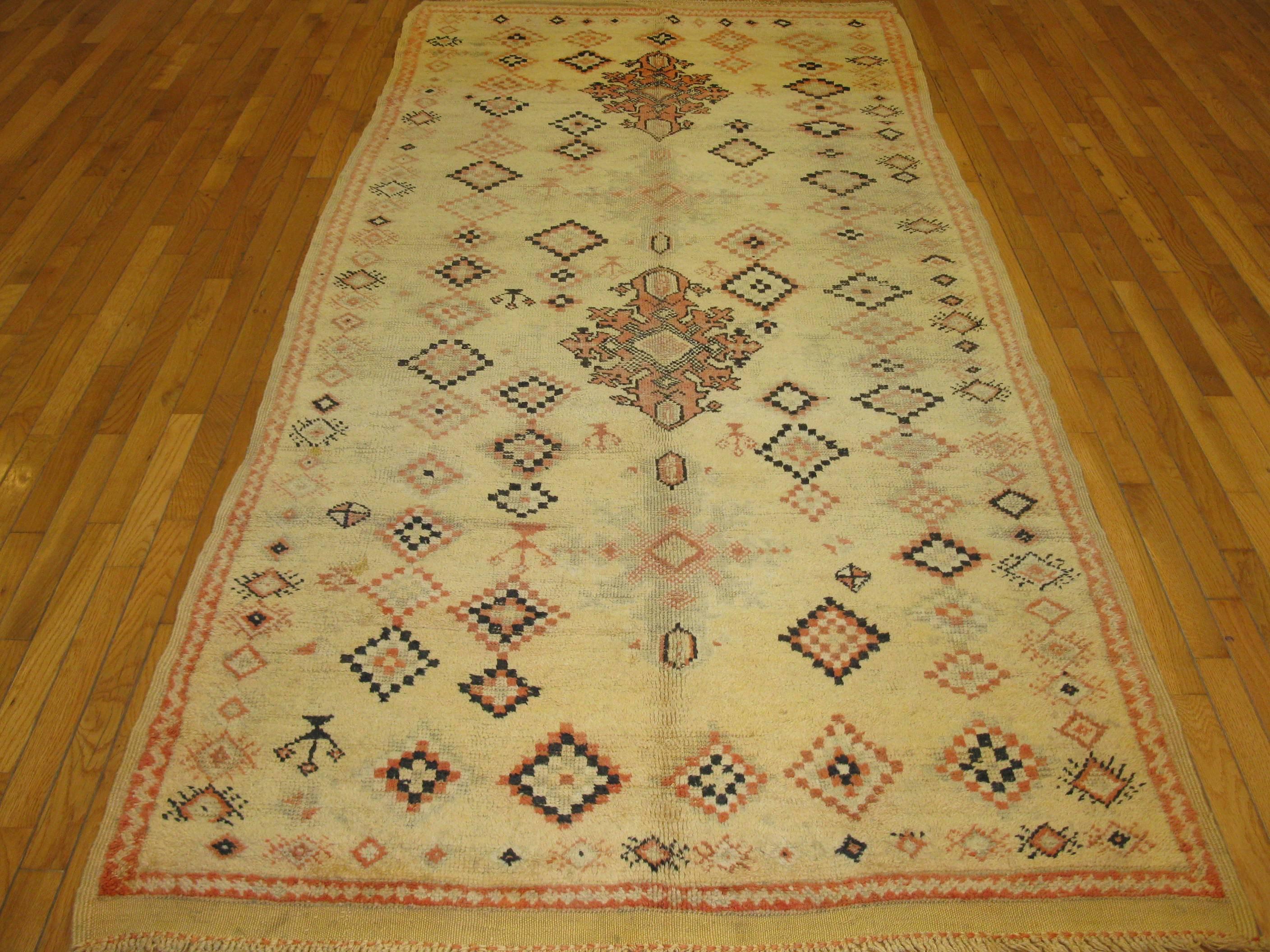 This beautiful hand-knotted vintage Moroccan rug has a simple tribal design with primary colors would enhance the look of any space. The rug is made with wool and all natural dyes. It measures 4' 4'' x 9' 6'' .