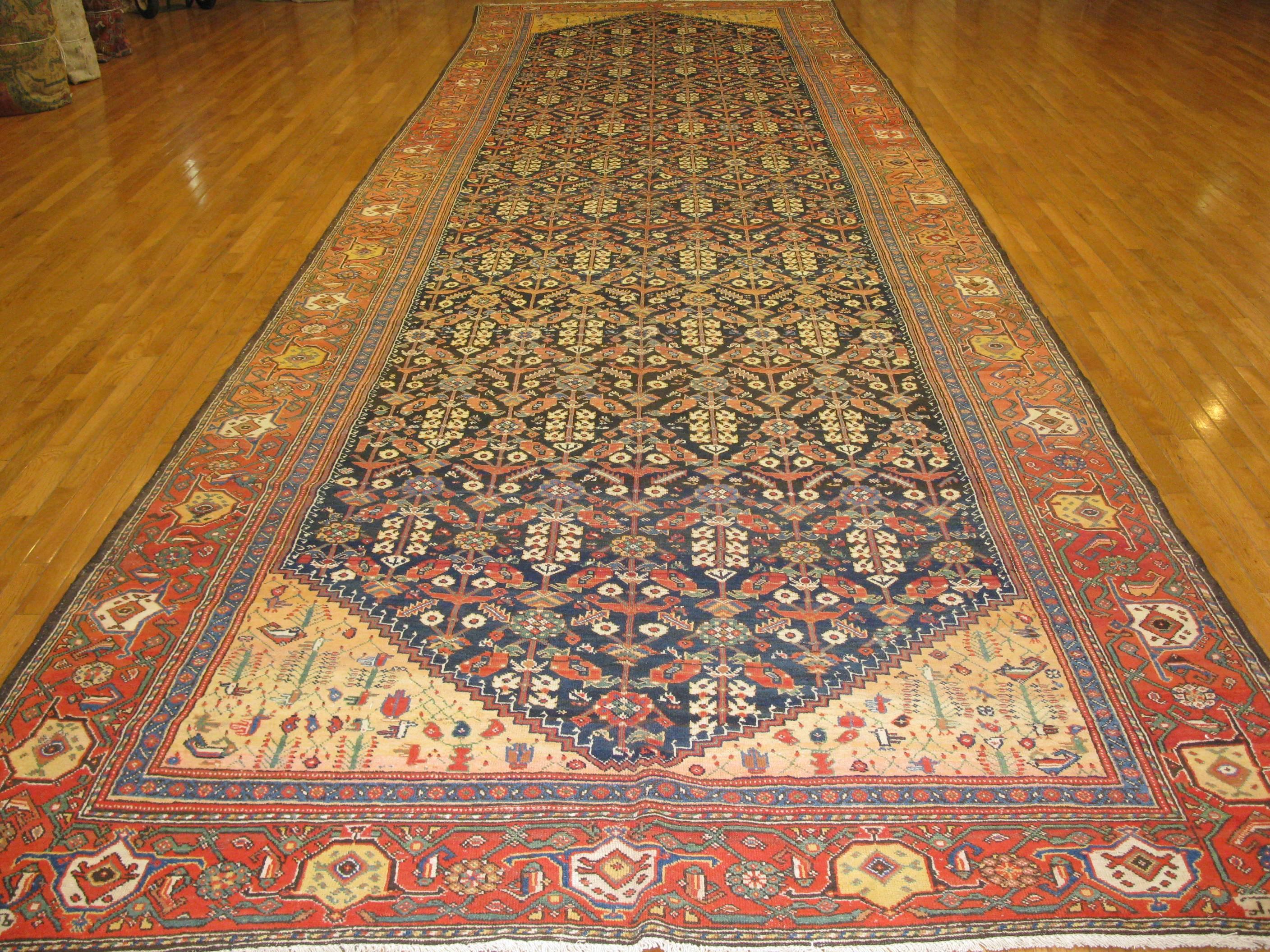 This rug is an exceptional antique oversized wide and long hand-knotted Persian Baktiary rug. It has an elegant detailed all-over pattern encased by a wide border. The rug measures 7' 3'' wide x 25' long handmade with wool and all natural colors. It