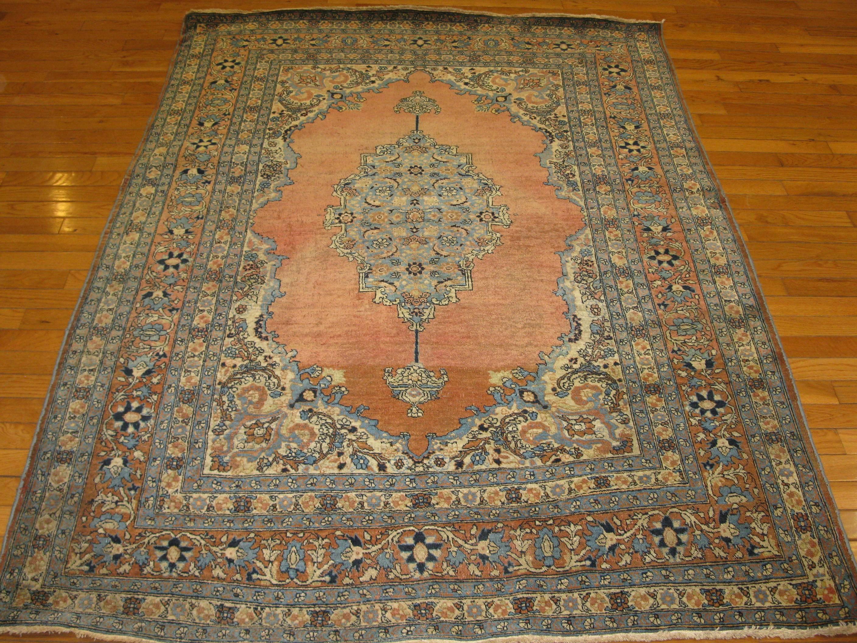 This is a beautiful hand-knotted small antique Persian Haji Jalili Tabriz rug. It has an intricate pattern on an open field in coral color background. The rug has a fine weave and measures 4' 8" x 6' 4" and in great condition.