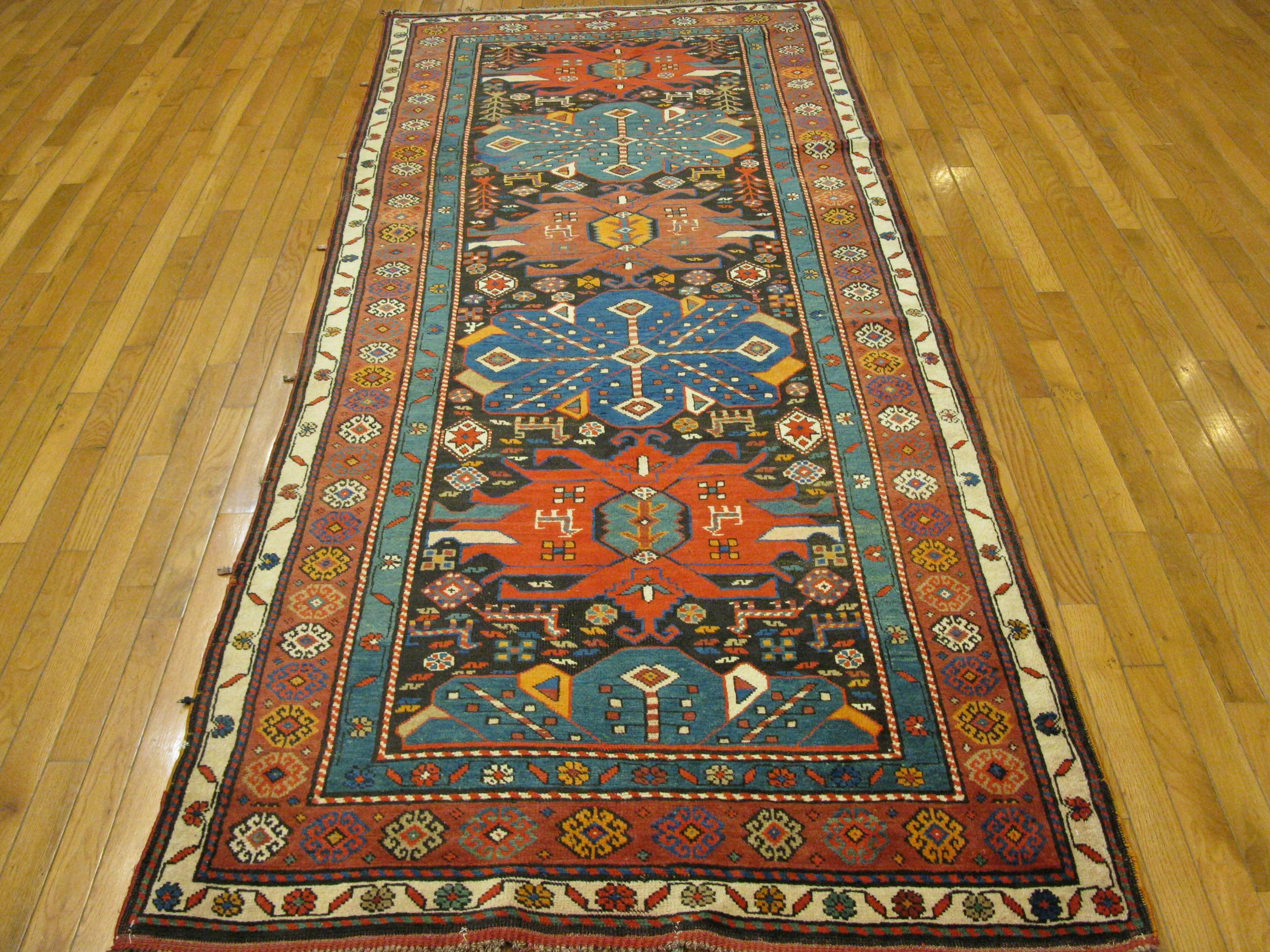 This short antique hand-knotted runner rug was made in the village of Kazak in the Caucuses with all wool and natural dyes. It measures 3' 9'' x 9' 9'' and it is in excellent condition.