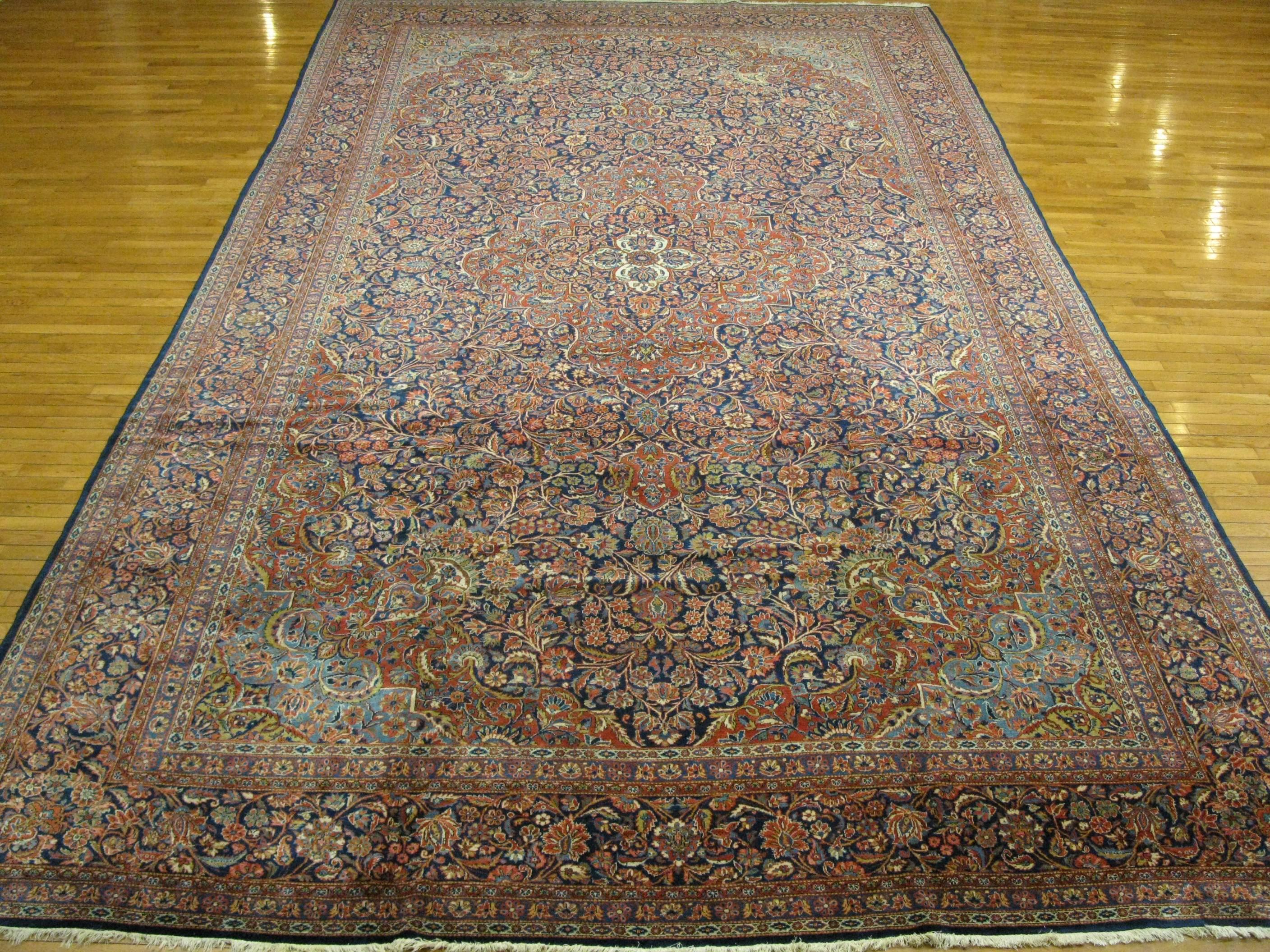 This is a fabulous antique hand-knotted Persian Kashan rug. It has a beautiful intricate floral pattern in the traditional central and corner medallion design. It is very finely knotted with wool colored with natural dyes. The rug is in great